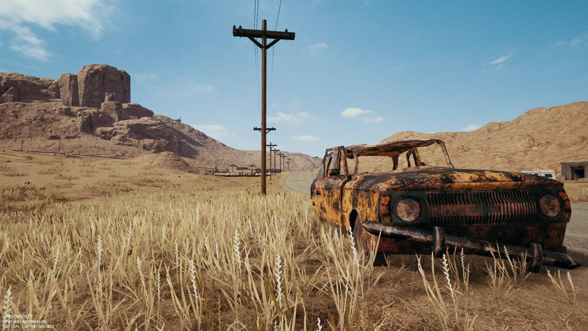 PUBG 3D 生動高清廢棄車輛 壁紙 — 一輛生鏽的經典汽車被遺棄在乾燥的草地上，背景是晴朗的藍天和岩石丘陵。