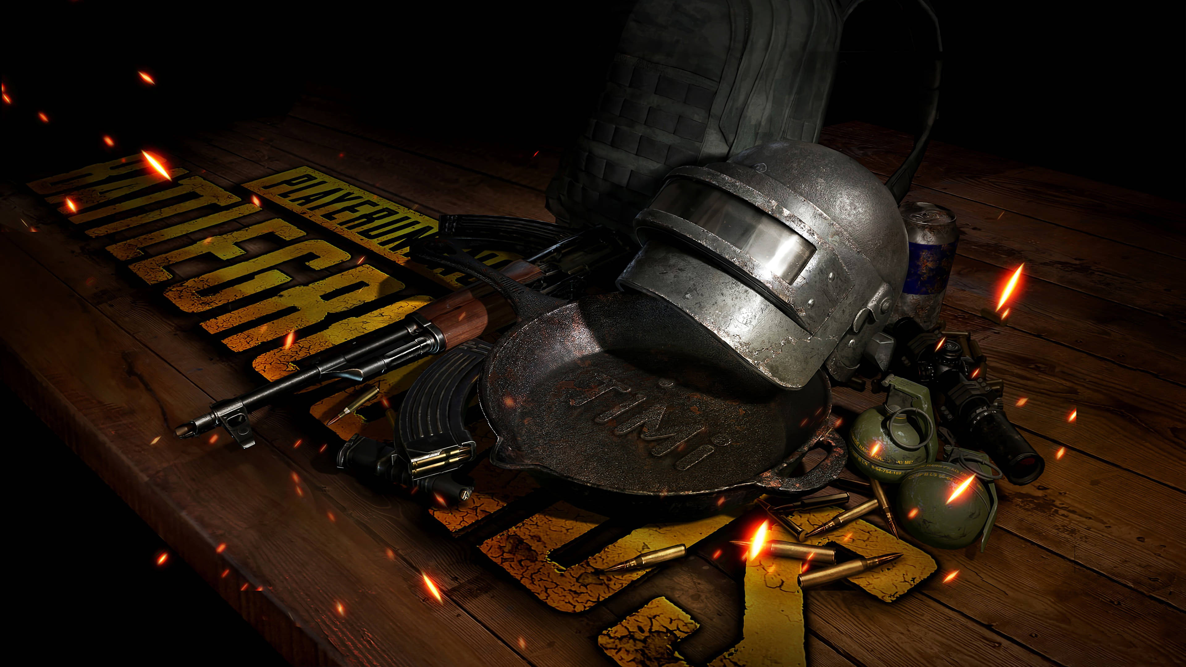 PUBG Lite 手機遊戲武器 壁紙 — 一個粗糙的PUBG頭盔、步槍和裝備放在木桌上，火花在遊戲標誌周圍飛舞。