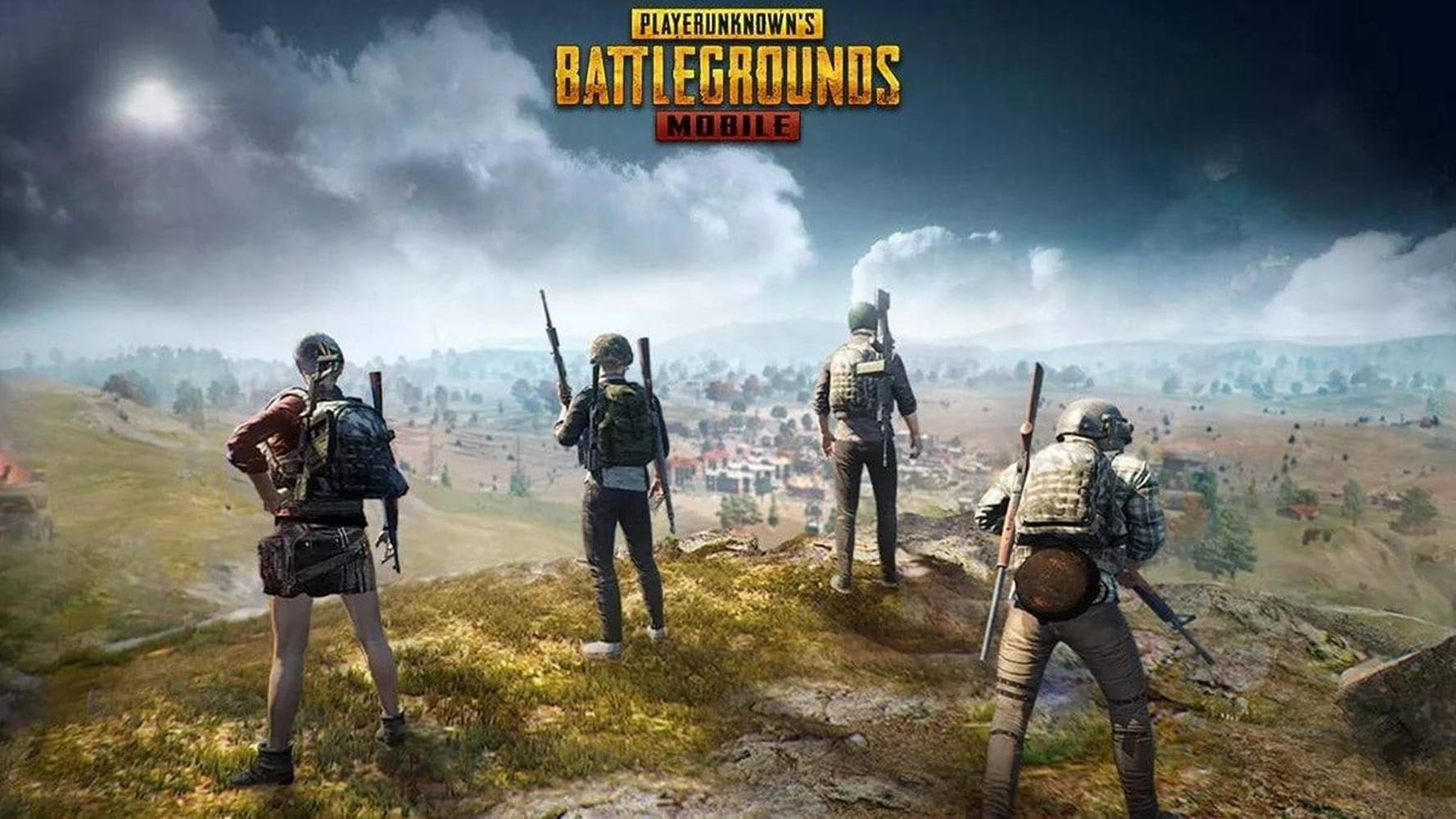 四名武裝玩家在PUBG Mobile中從山丘上俯瞰小鎮。