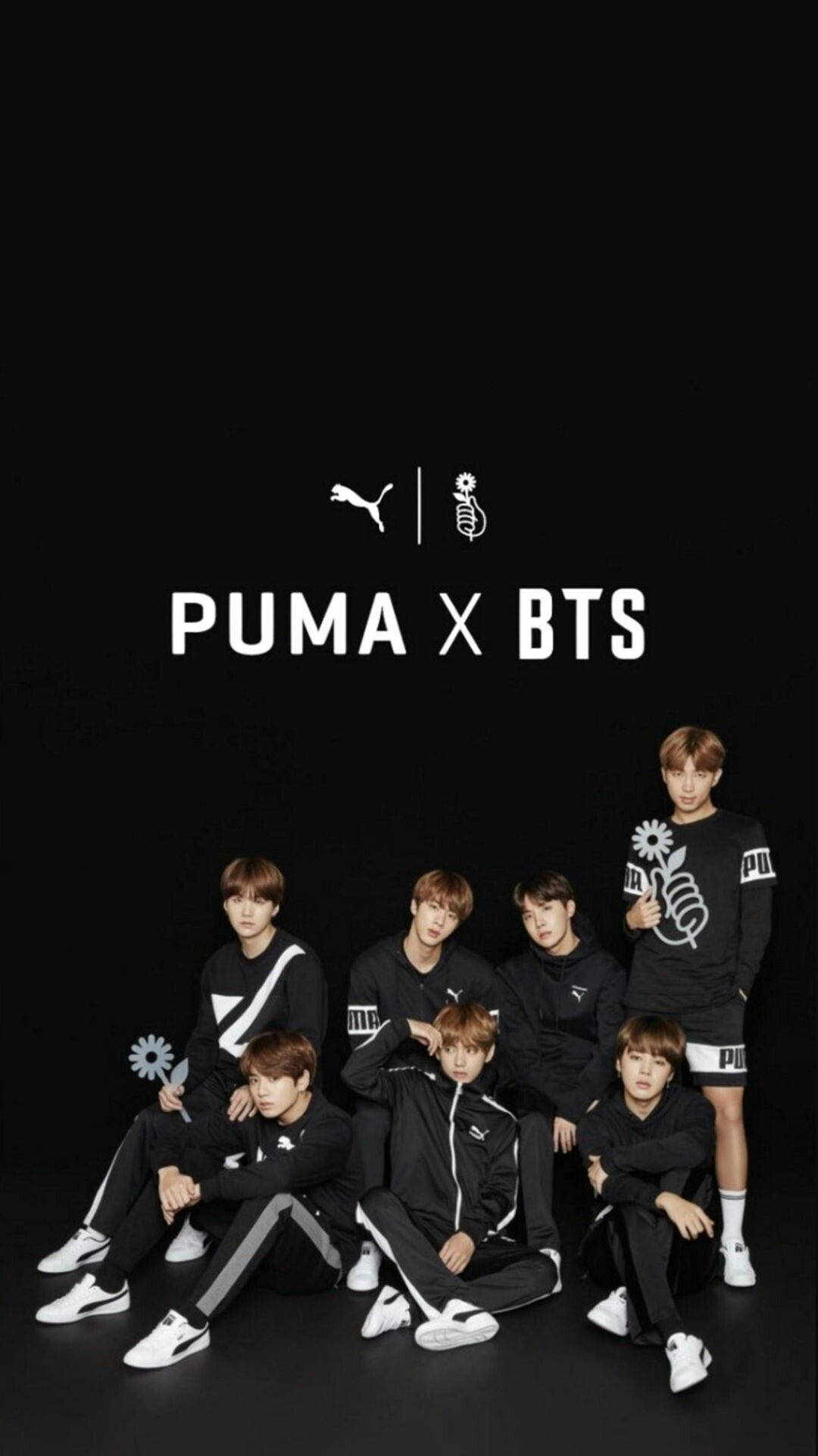 七名身穿黑色 Puma 服裝的 K-pop 偶像為品牌合作照片擺姿勢。