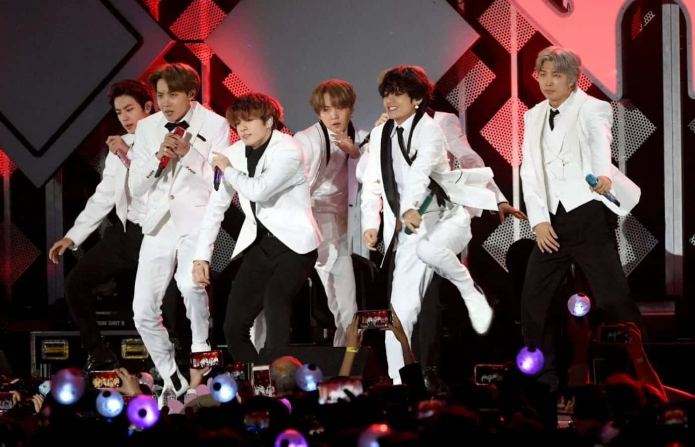 K-pop 組合在舞台上表演，粉絲高舉發光手機。