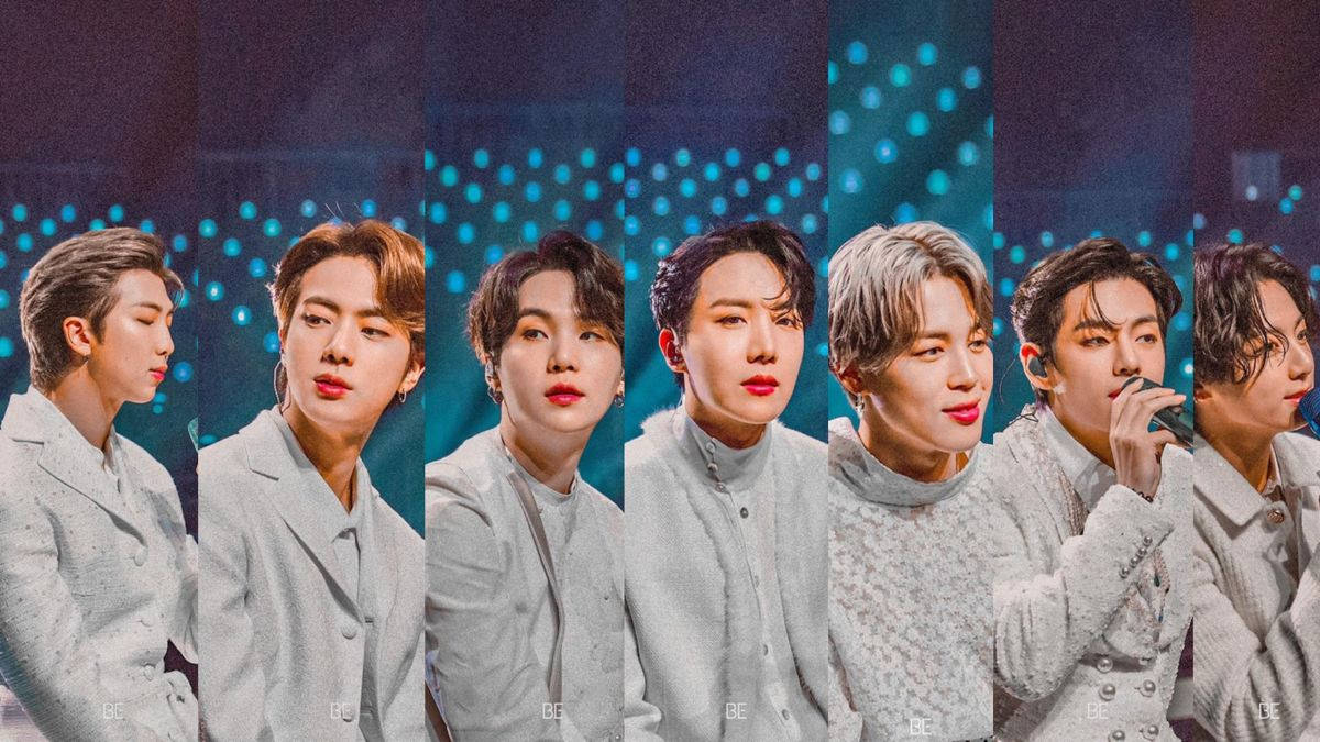 七位身穿灰色服裝的K-pop偶像在藍色燈光舞台上。