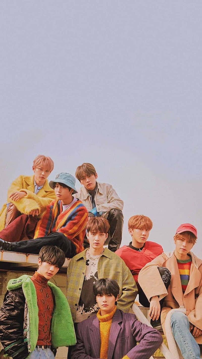 七位身穿色彩繽紛服裝的時尚年輕男子在屋頂上擺姿勢。 — Stray kids GIF 壁紙