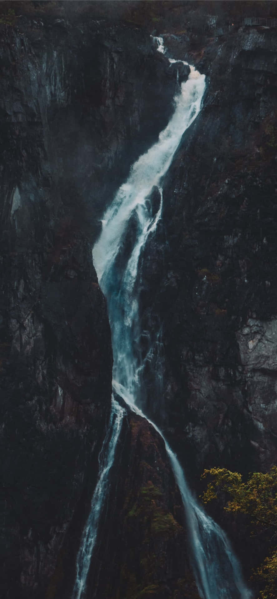  壁紙 — 一道強勁的瀑布從黑暗崎嶇的懸崖傾瀉而下，下方水潭升起薄霧。