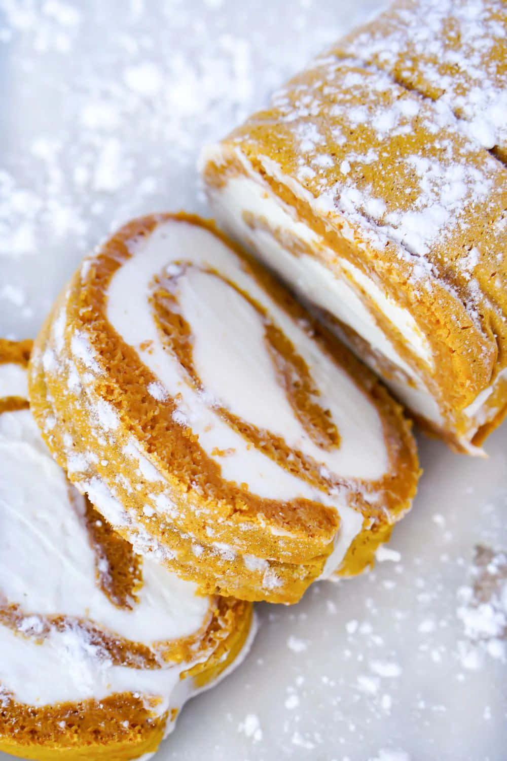  壁紙 — 切片南瓜卷蛋糕撒上糖粉，在大理石表面上顯露出奶油漩渦。