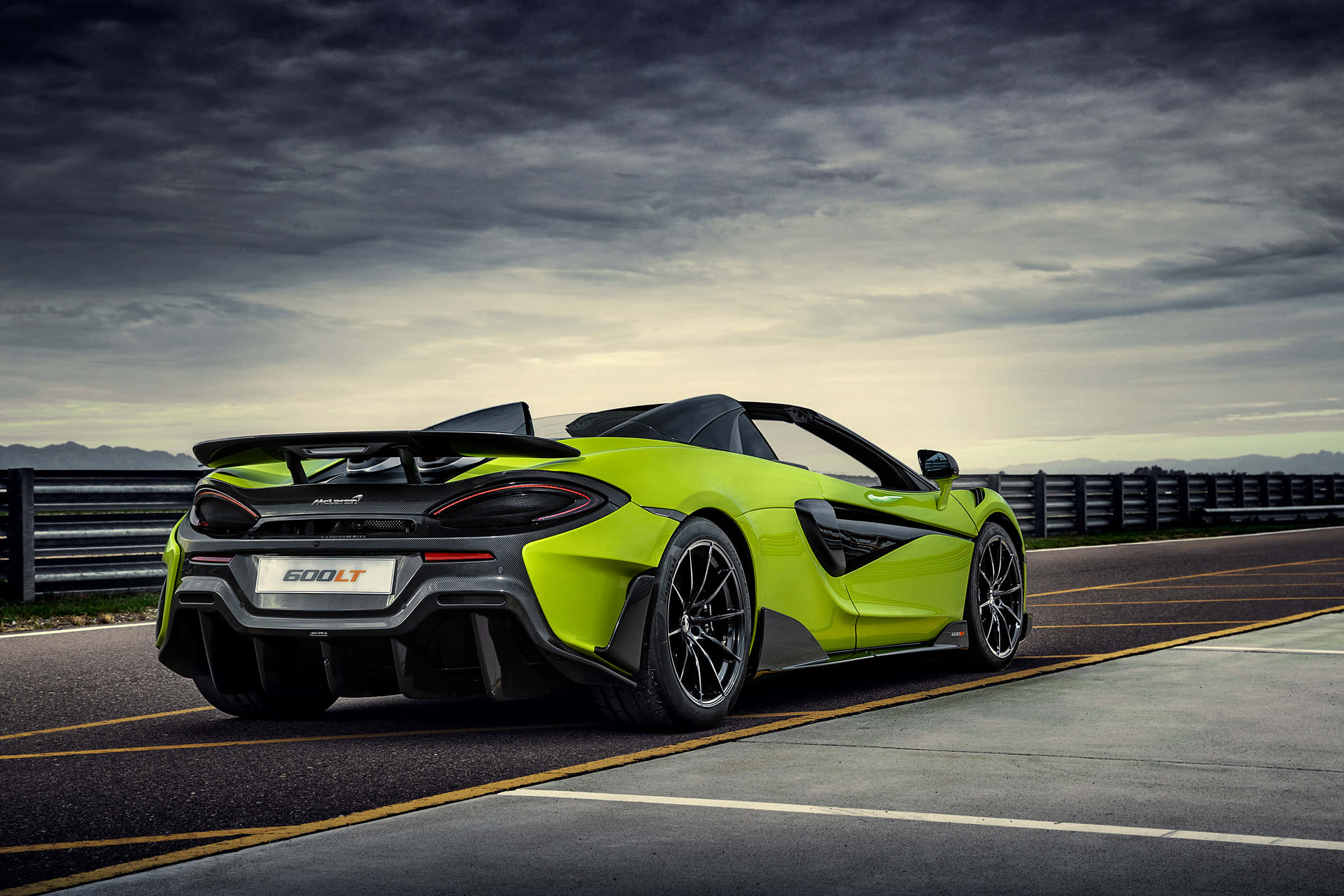 Mclaren 600lt Spider 桌布 壁紙 — 一輛充滿活力的青檸綠色McLaren 600LT Spider跑車停泊在賽道上，天空戲劇性地多雲。