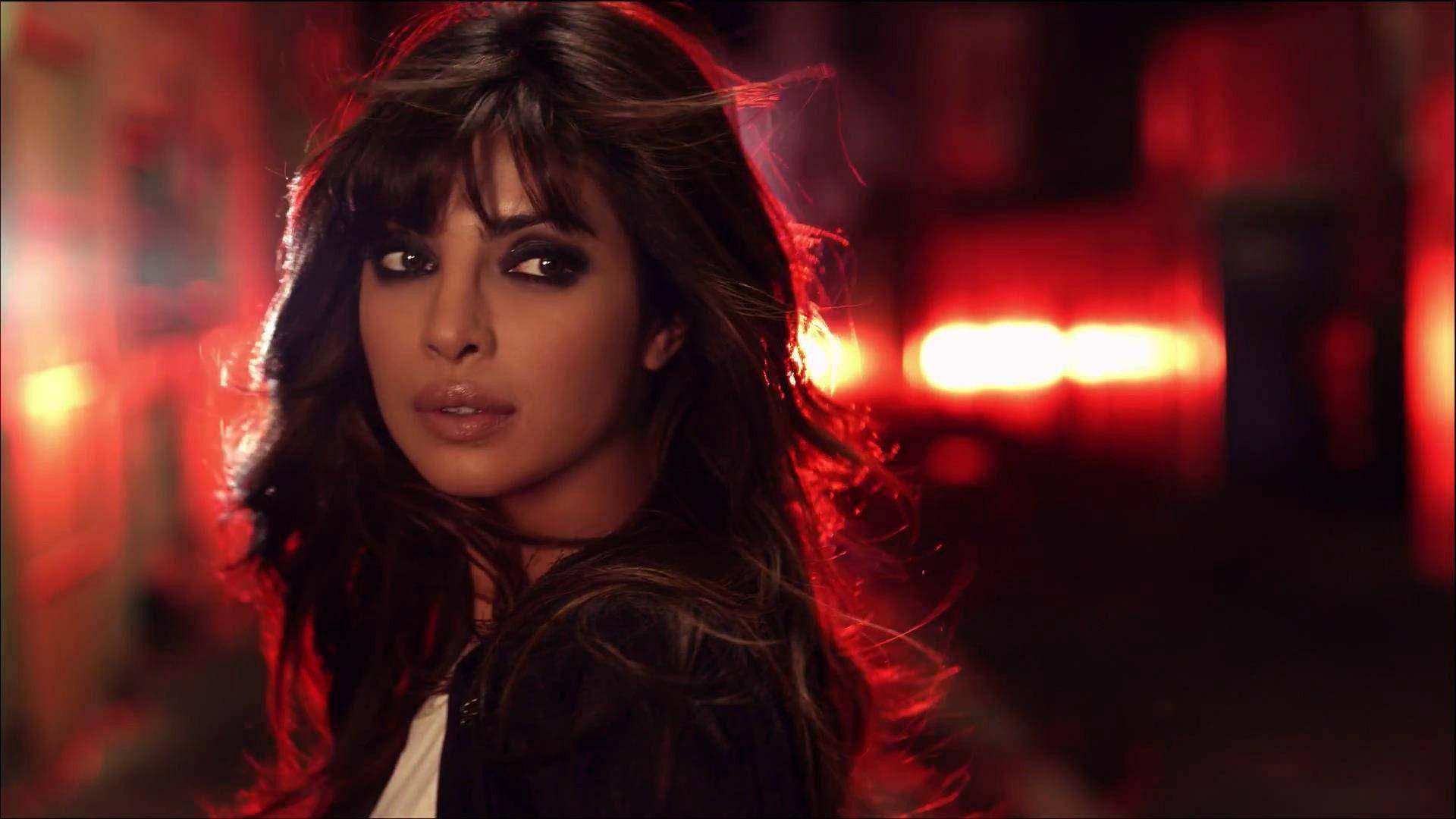 《Quantico》主角亞歷珊德拉·帕里什 壁紙 — 一位深色頭髮、煙熏眼妝的女性，在模糊的紅色城市背景下凝視著。
