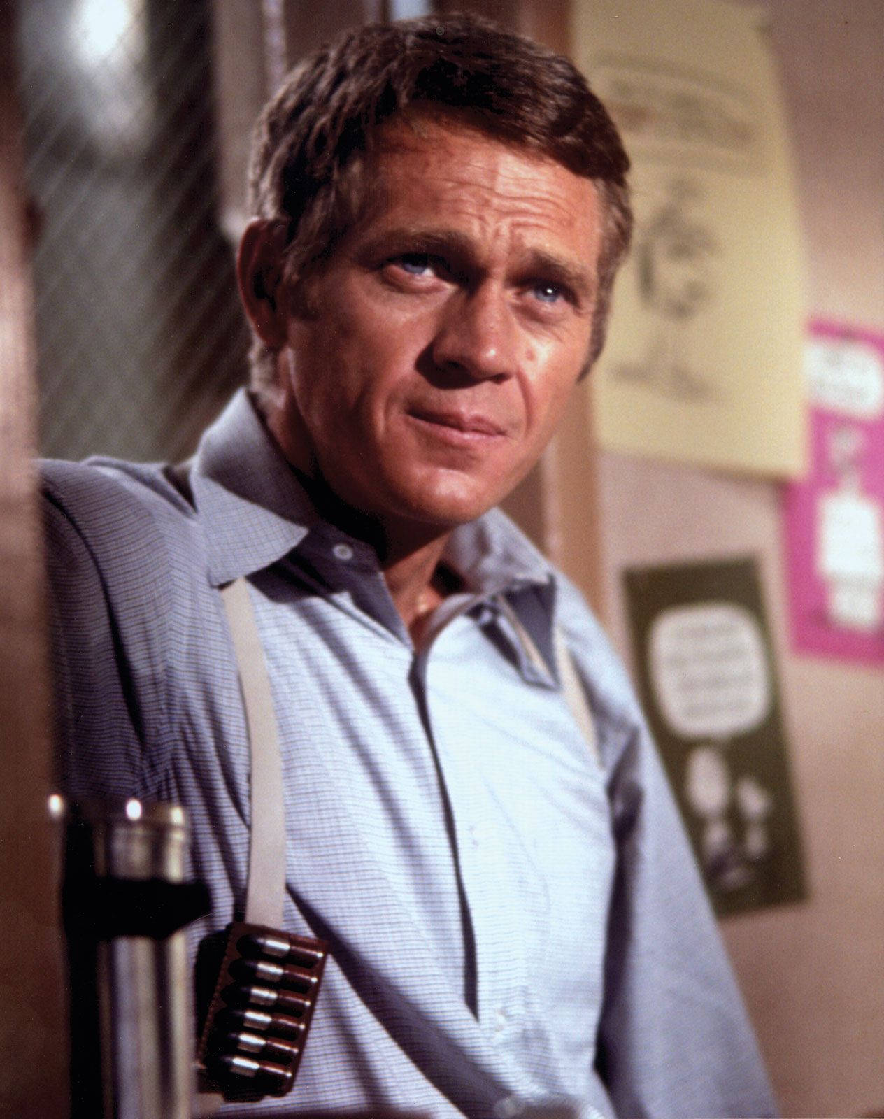 美國演員史蒂夫·麥克queen 在1968年《Bullitt》電影劇照 壁紙 — 一個穿著格仔恤衫和吊帶的男人，神情嚴肅地凝視著，同時拿著咪高峰。