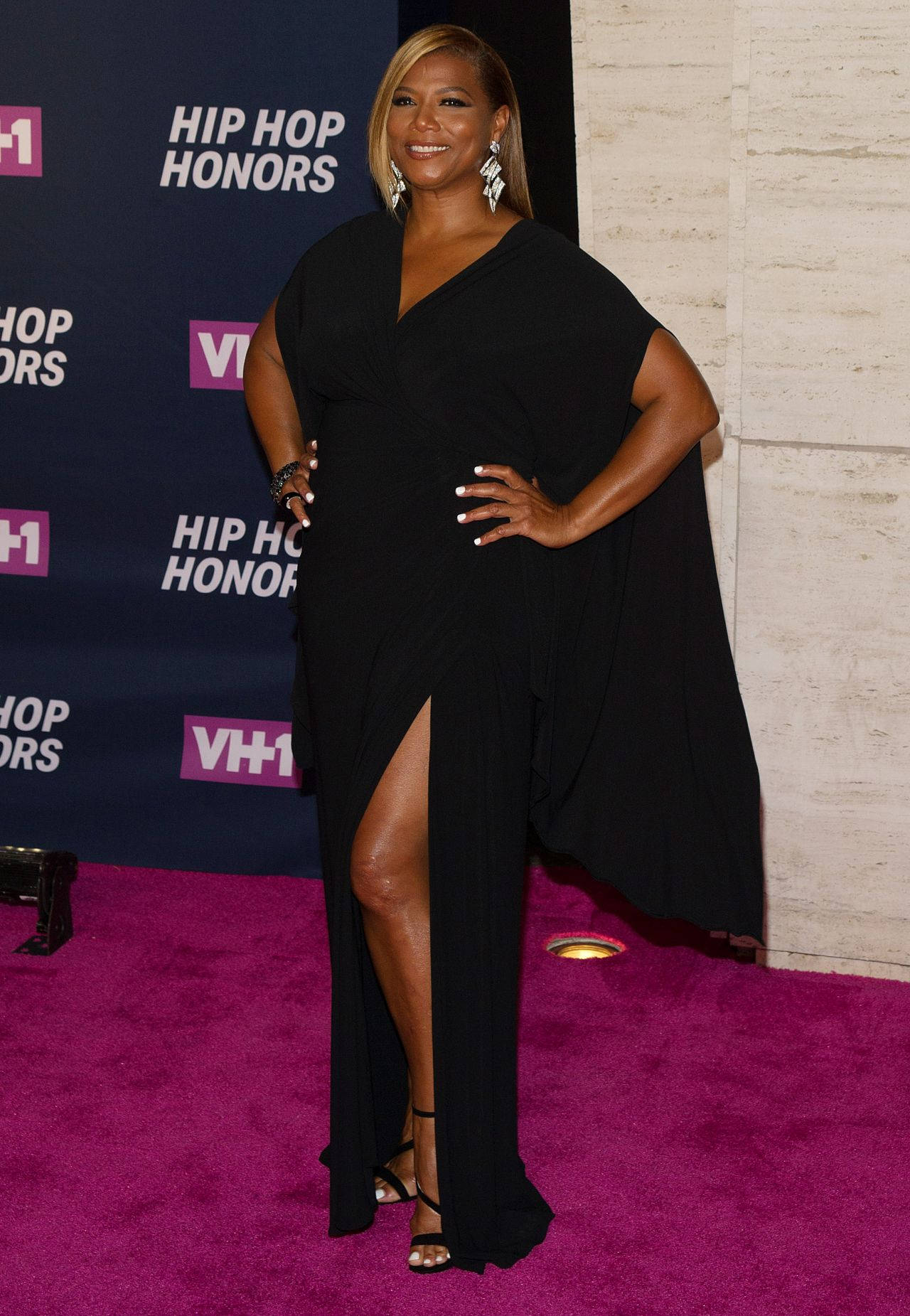女性身穿黑色禮服在VH1 Hip Hop Honors活動的紫色地毯上擺姿勢。