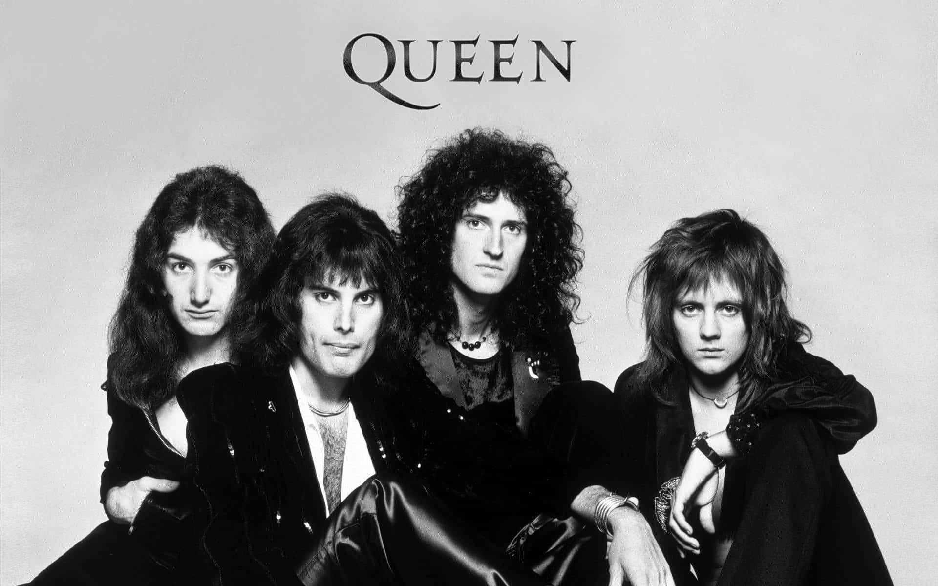 Queen樂隊經典陣容：Freddie Mercury、John Deacon、Brian May與Roger Taylor 壁紙 — 搖滾樂隊Queen的黑白工作室肖像，帶有強烈的目光和戲劇性的70年代髮型。