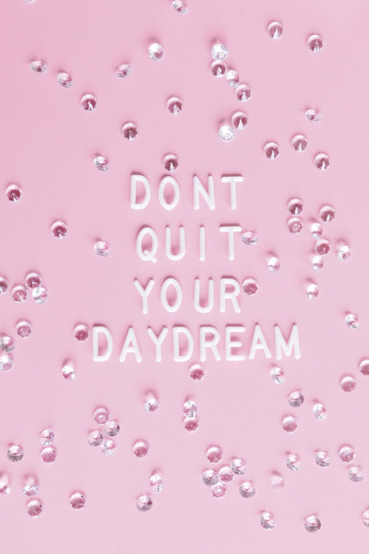 粉紅色背景，白色3D文字寫著「DON'T QUIT YOUR DAYDREAM」，周圍環繞著銀色水鑽。