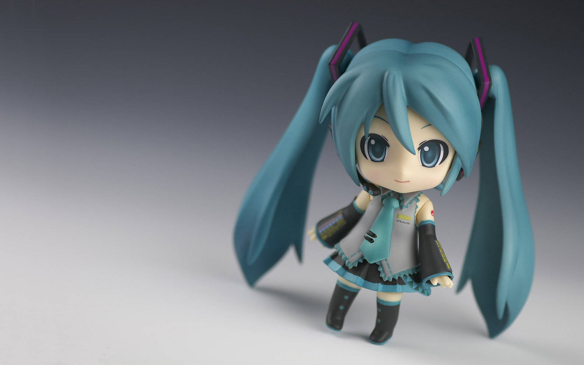 Q版初音未來公仔，藍綠色雙馬尾和藍色眼睛，灰色背景。