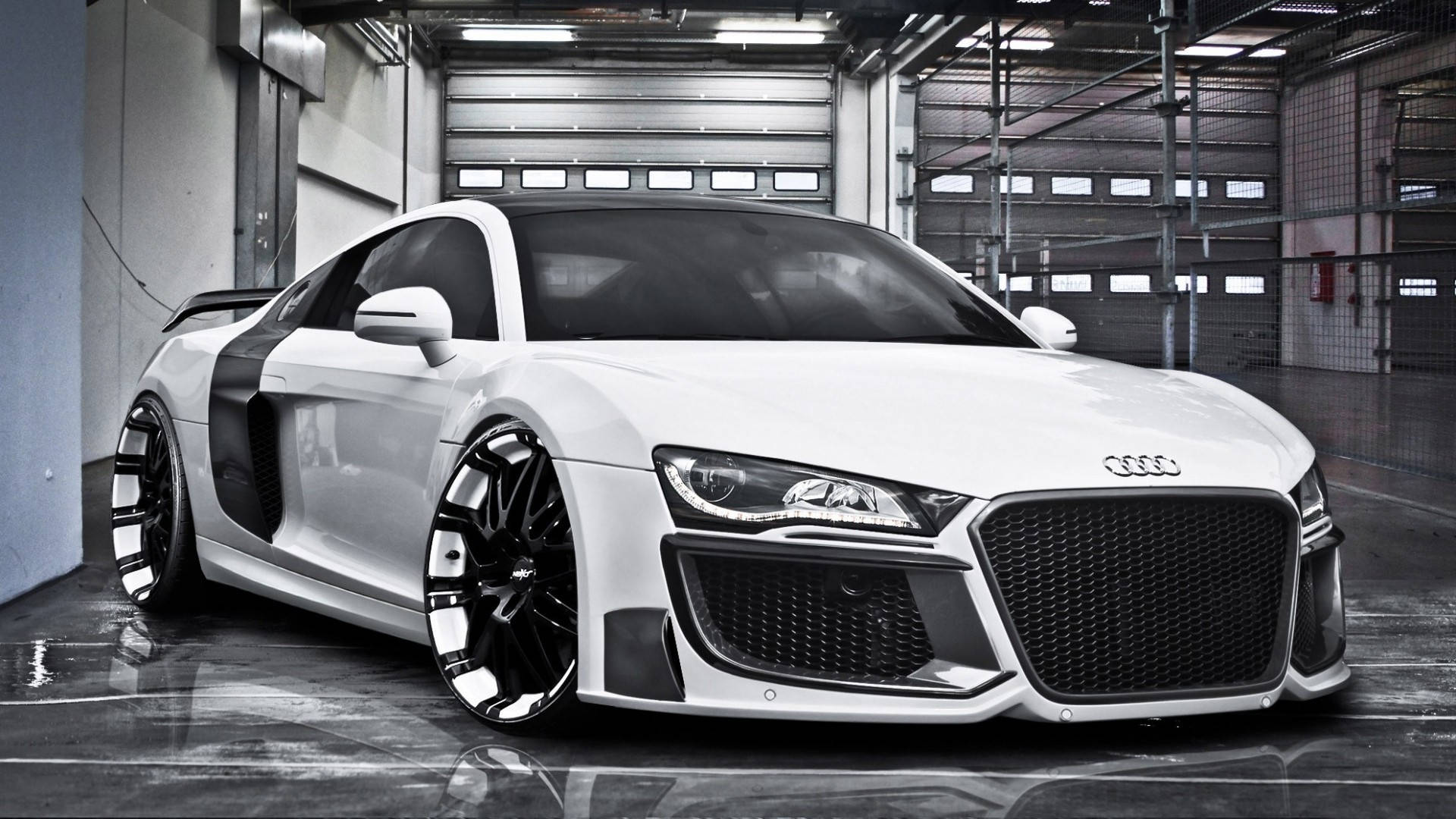 白色奧迪R8 V10特調版 壁紙 — 一輛時尚的白色奧迪R8跑車，帶有黑色飾件和定制輪圈，停放在寬敞的工業車庫中，地板具有反射效果。