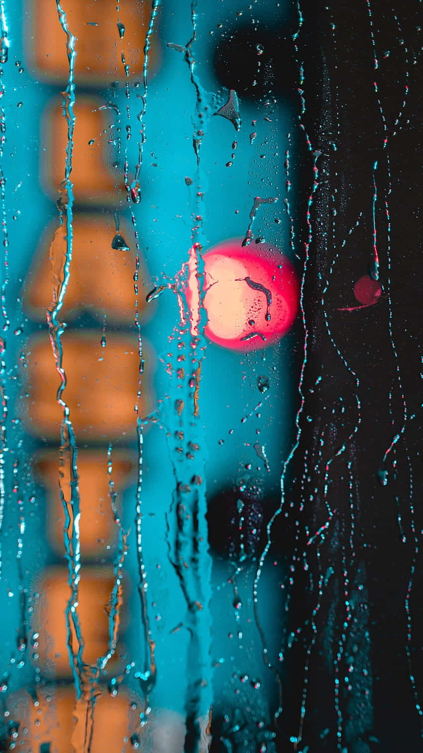 Abstract Water 桌布 壁紙 — 雨水沿窗流下，顯露出模糊的城市景觀，在青綠色和橙色調中有一個發光的粉紅色圓形燈光。