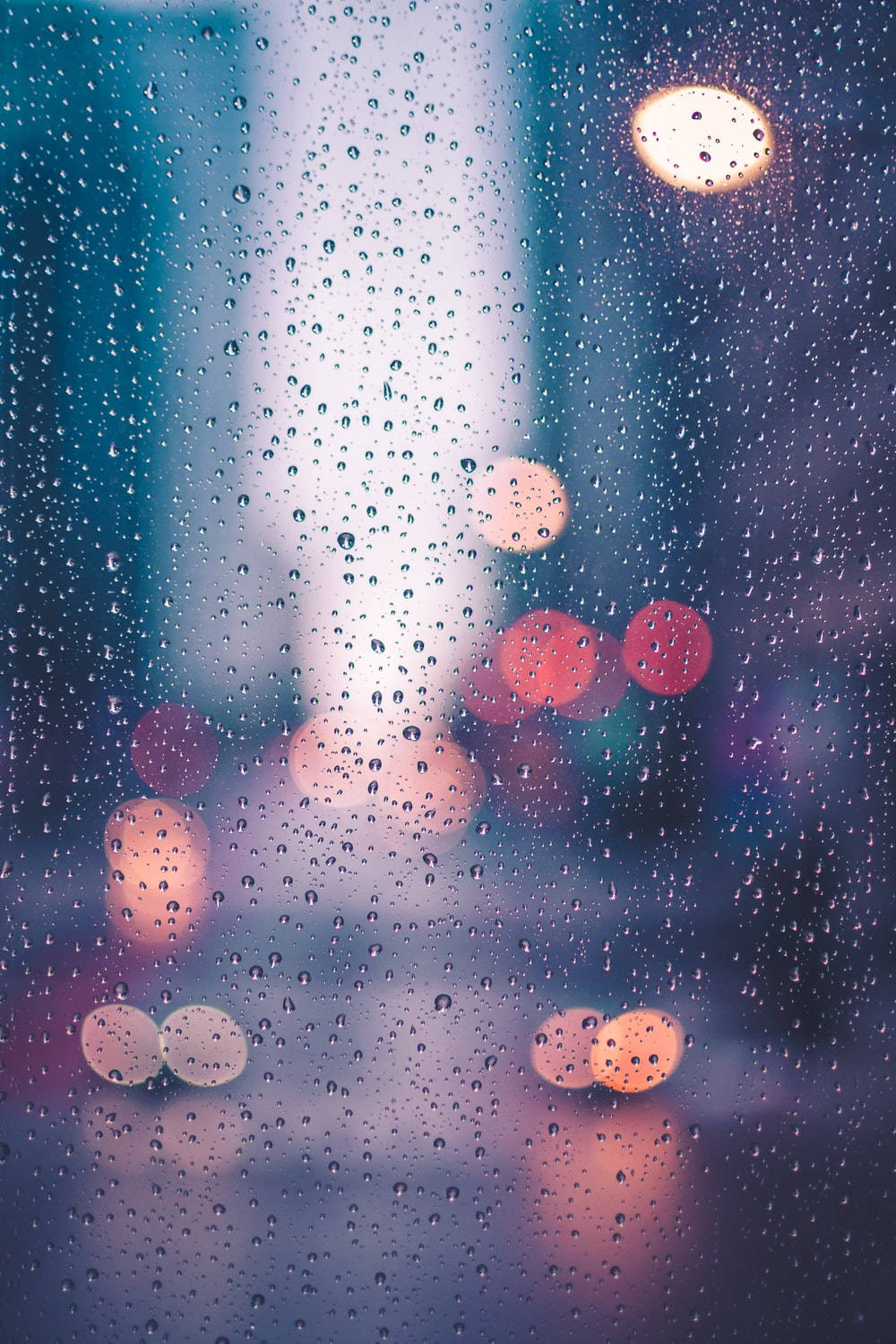 窗戶上的雨滴，夜晚中模糊的城市燈光閃爍。