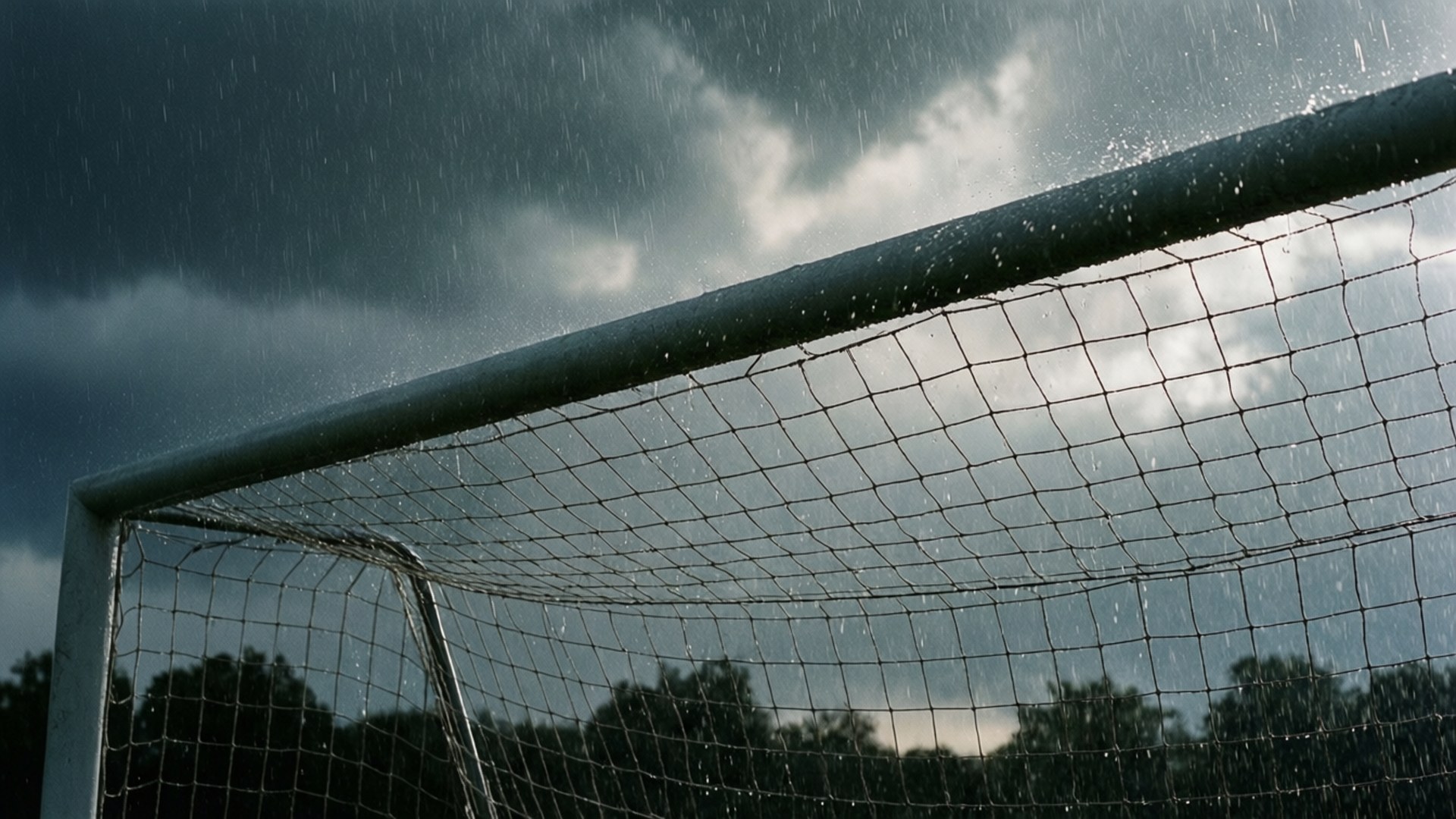 Goal Post 桌布 壁紙 — 雨滴沿著足球龍門網流下，下方是黑暗風暴天空和剪影樹木。