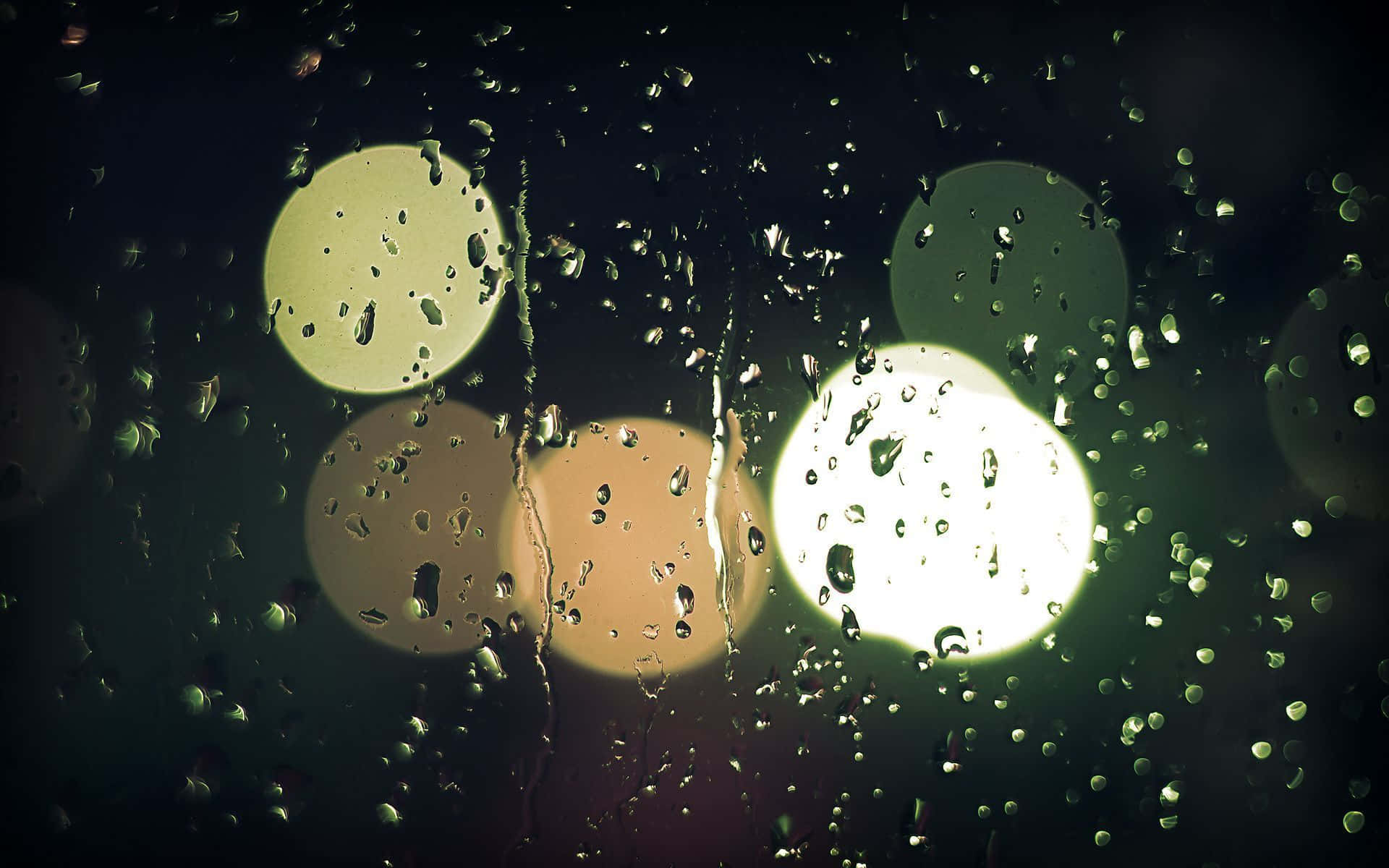 窗戶上的雨滴，模糊的路燈在黑暗中發光。