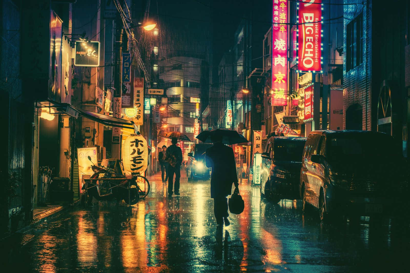 夜晚在潮濕的霓虹燈日本街道上撐傘行走的人。