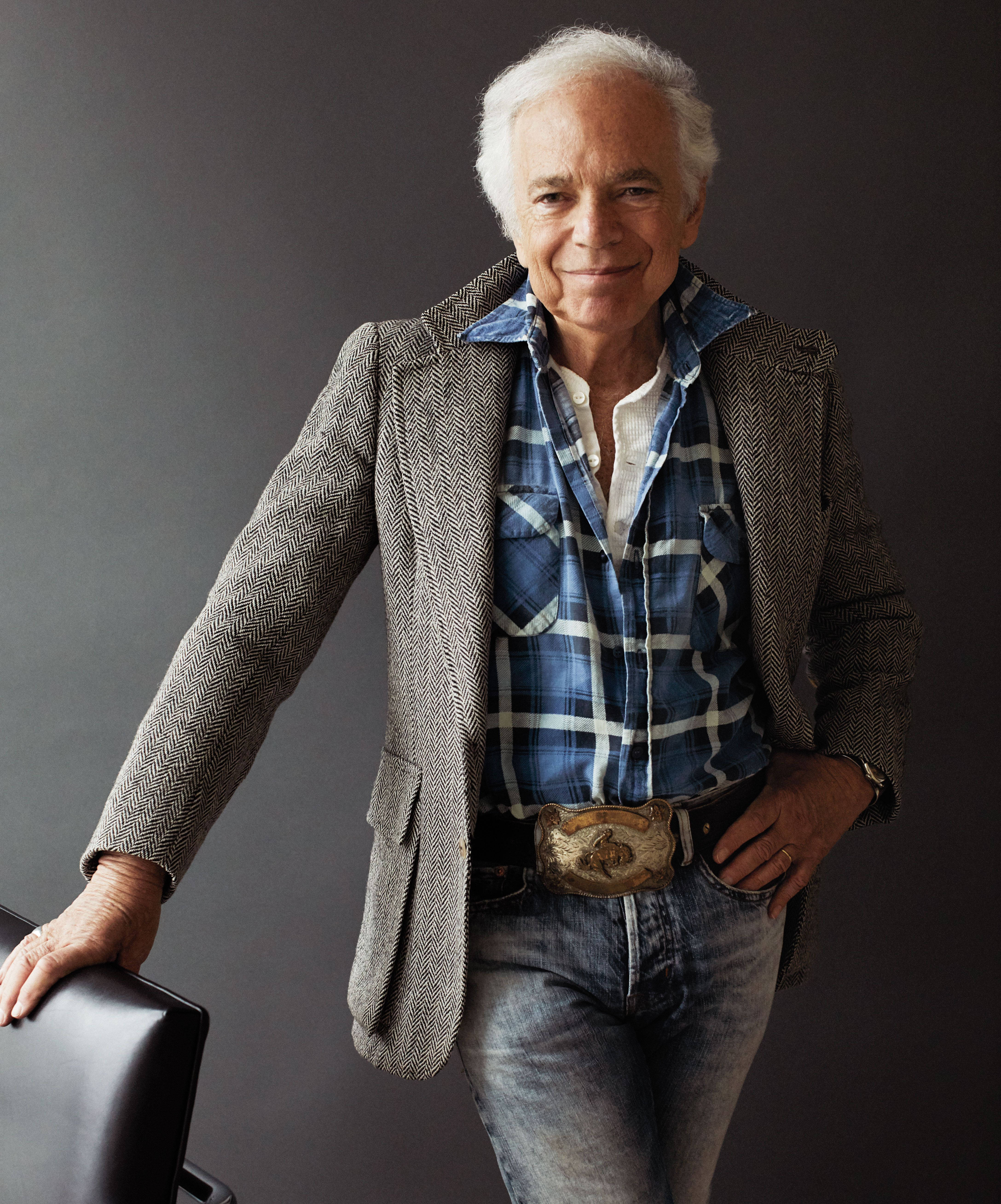 Ralph Lauren 牛仔褲 壁紙 — 一位白髮的時尚年長男士微笑著靠在椅子上，穿著人字紋西裝外套和格仔襯衫。
