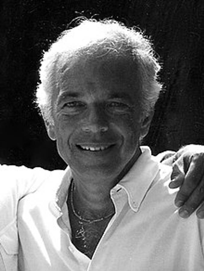 Ralph Lauren 黑白肖像 壁紙 — 一位微笑的白髮老年男士穿著白襯衫和項鍊的黑白肖像。