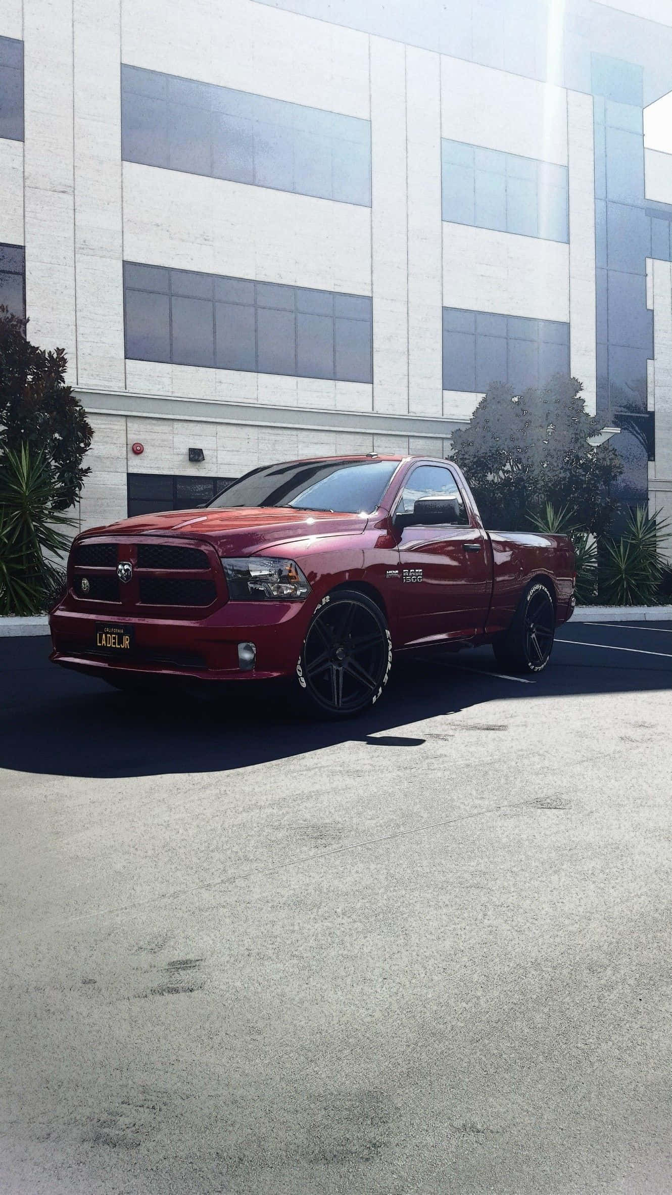 低趴卡車道奇Ram SRT-10 壁紙 — 一輛光澤紅色Ram皮卡車配黑色輪圈，停在一棟現代玻璃和混凝土建築前。