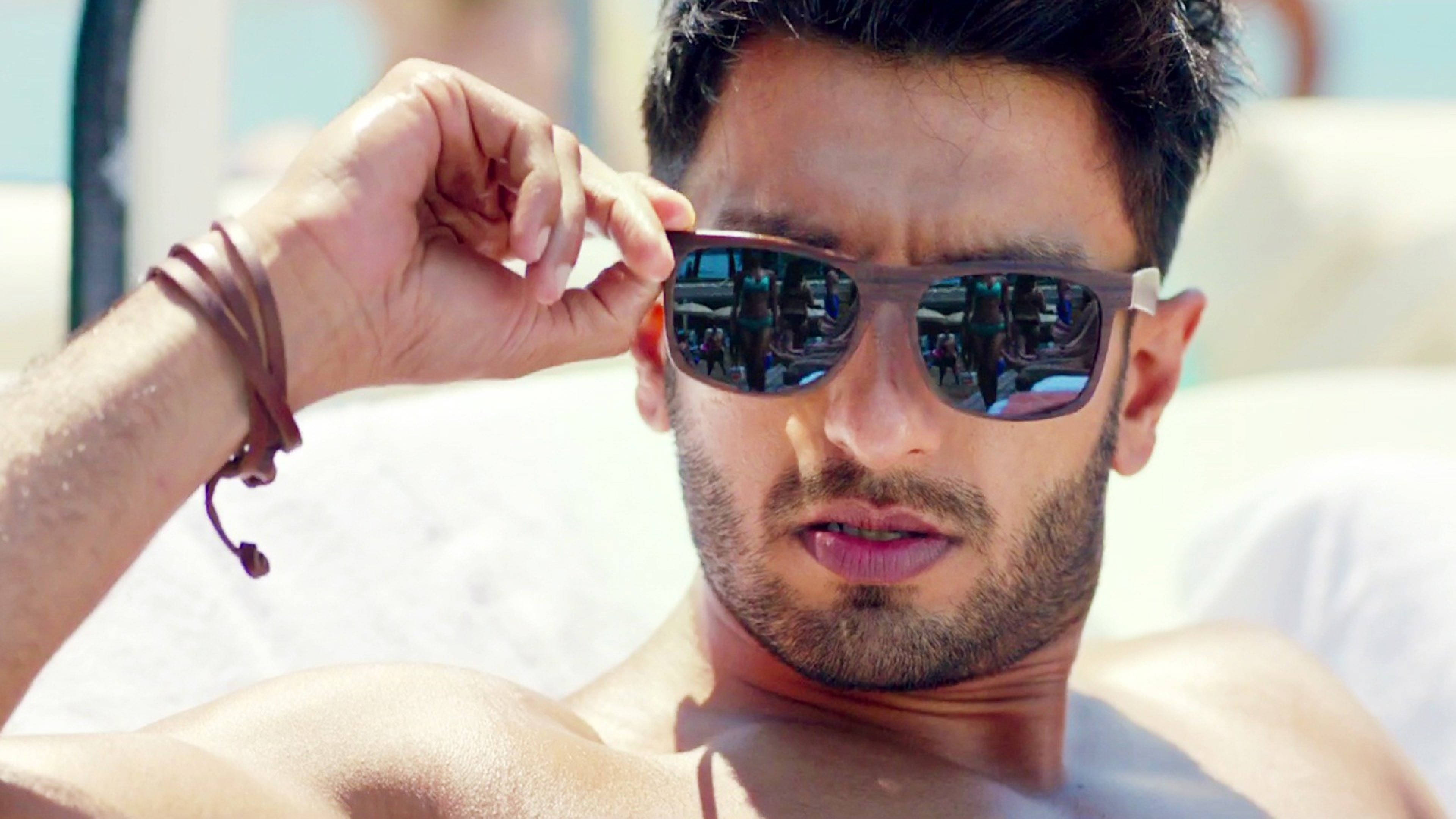 Ranveer Singh 在《Befikre》電影中 壁紙 — 一個冇著衫、深色頭髮同鬍鬚嘅男人，喺陽光普照嘅沙灘椅上放鬆緊，同時調整佢嘅太陽眼鏡。