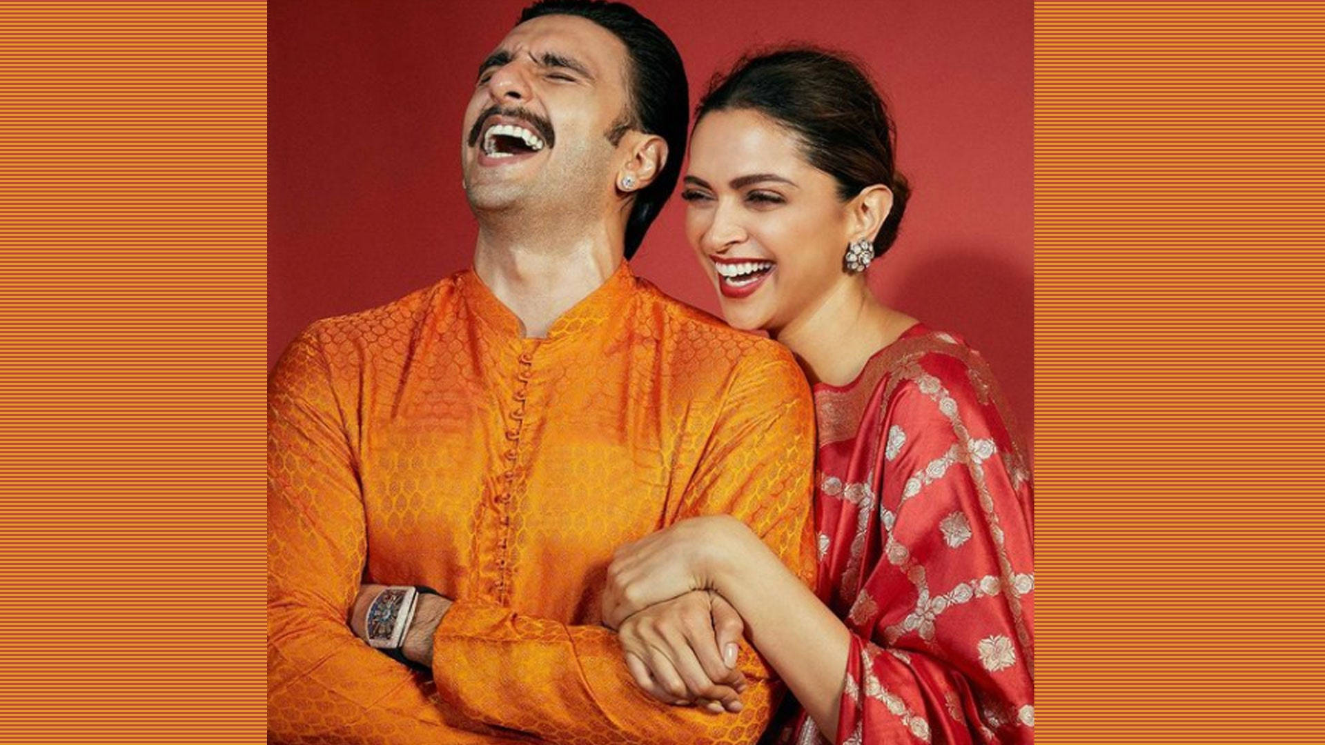 Ranveer Singh 與妻子 Deepika 的甜蜜合照 壁紙 — 一對快樂的情侶穿著傳統印度服飾，在溫暖的紅橙色條紋背景前一起大笑。