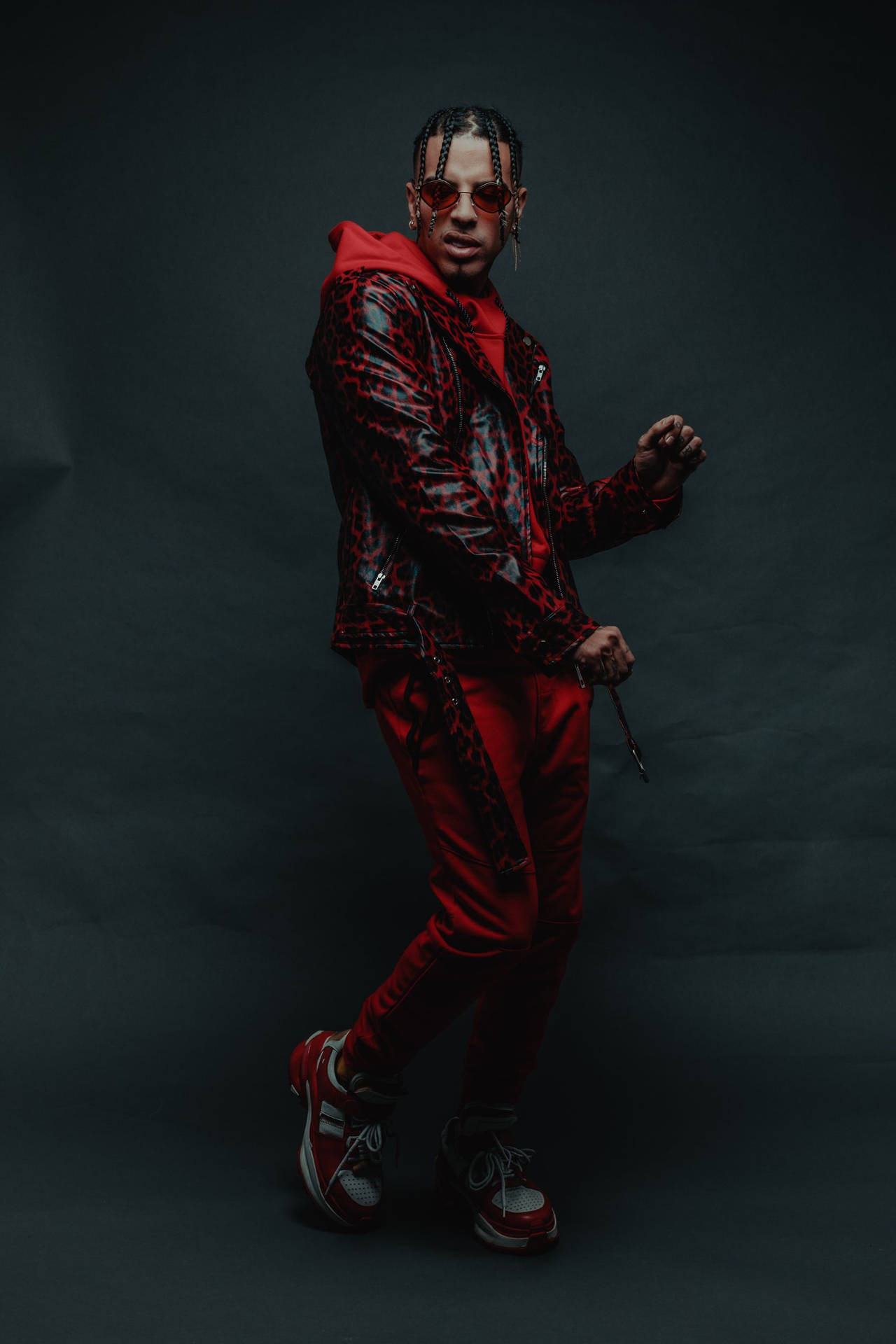 身穿紅色豹紋套裝的男士在攝影棚戴太陽眼鏡擺姿勢