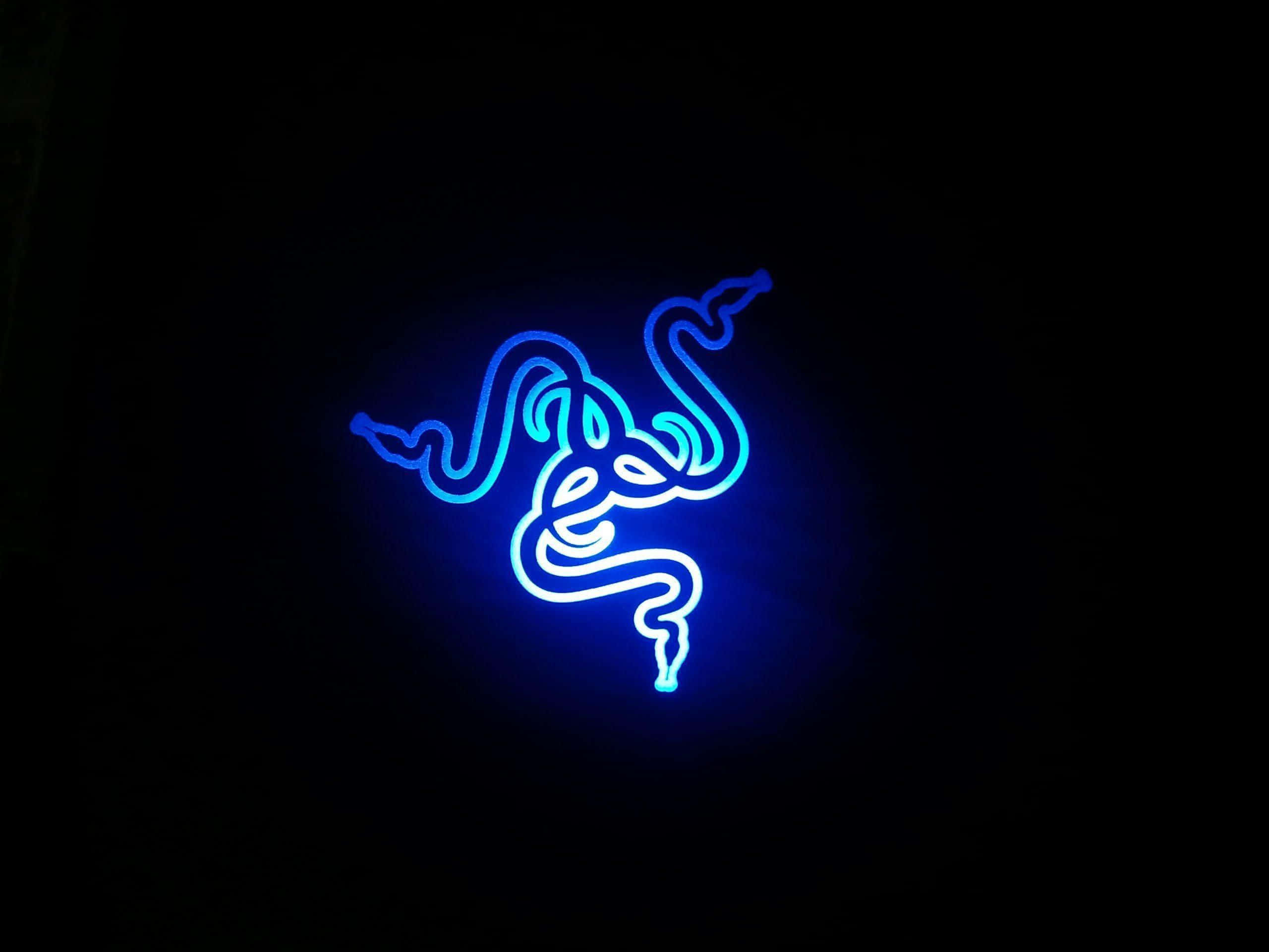 遊戲巨擘 Razer 帶來令人興奮的未來科技 壁紙 — 在漆黑背景上，一個發光的藍色霓虹燈標誌，顯示一條盤繞的三頭蛇。