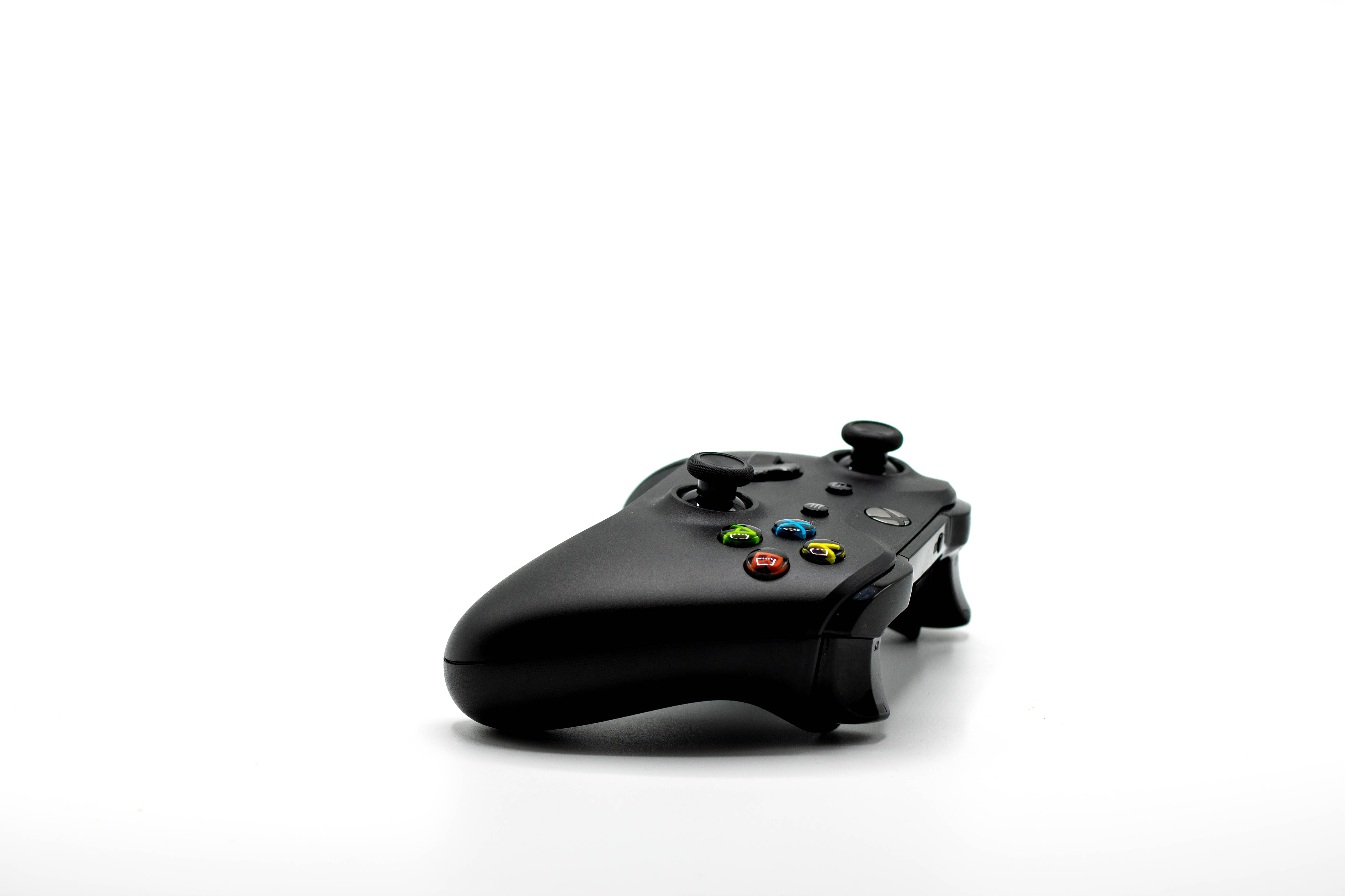 遊戲升級：Razer 遊戲滑鼠實戰表現 壁紙 — 一個時尚的黑色Xbox控制器，帶有彩色按鈕，放置在潔白的表面上。