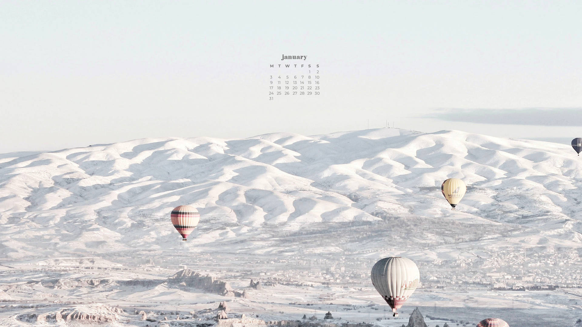 熱氣球漂浮在雪丘上空，天空有一月日曆。