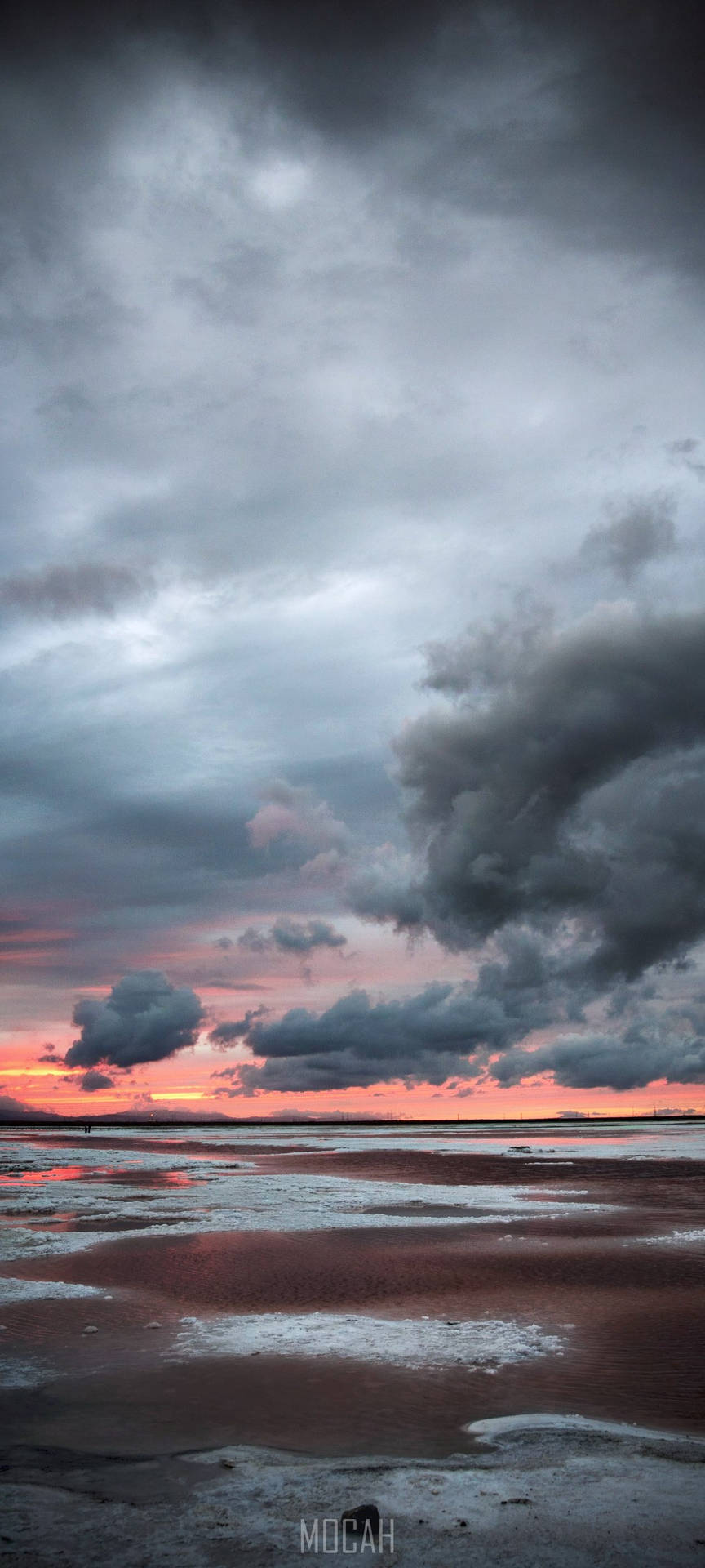 暴風雲下濕灘上的戲劇性夕陽。