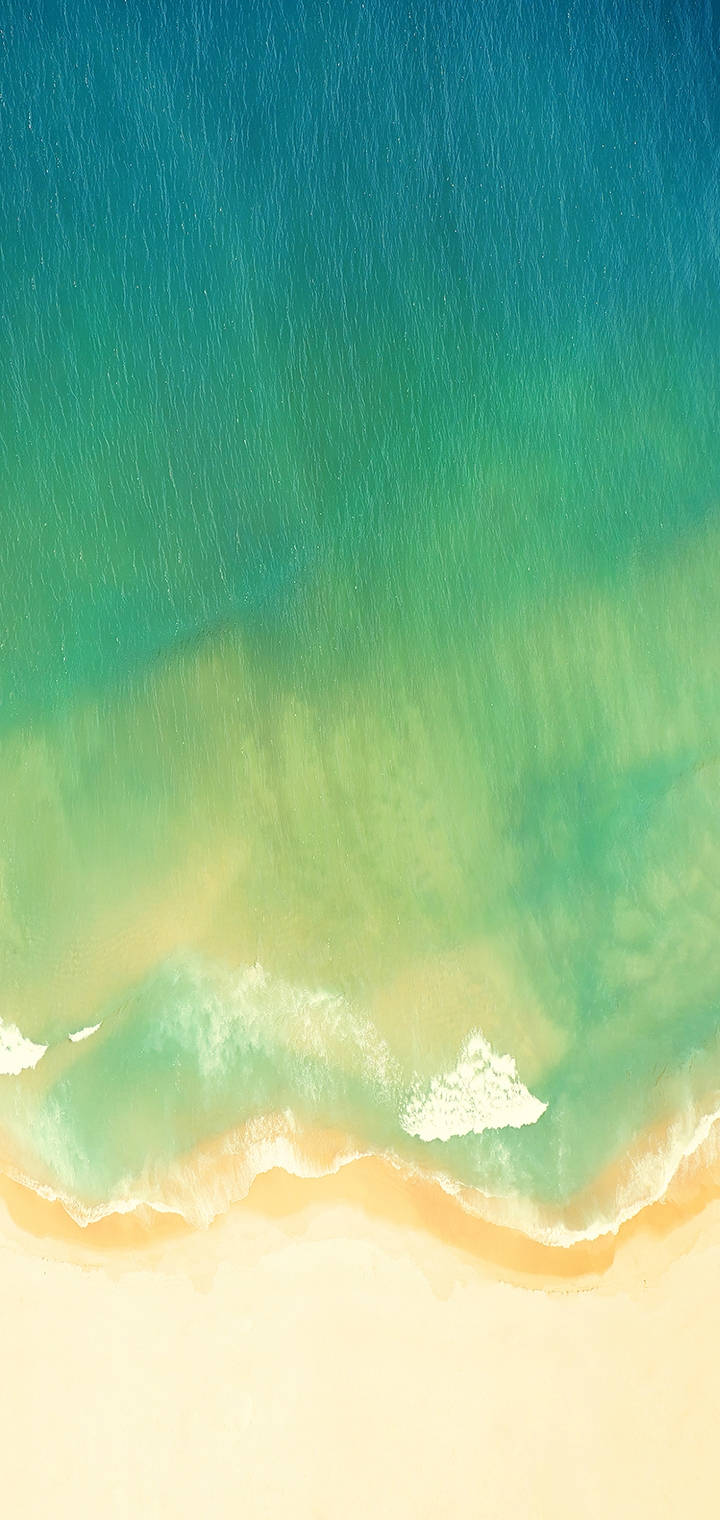 Realme 綠色海灘 壁紙 — 從高空俯瞰，碧綠的海浪輕輕拍打著淺色沙灘，泛起柔軟的白色泡沫。