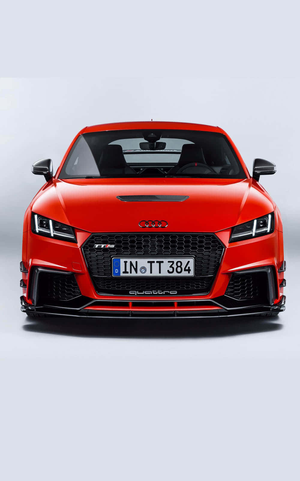 Audi Tt Rs 桌布 壁紙 — 一輛鮮紅色的奧迪TT RS跑車面向正前方，背景是潔淨的白色攝影棚，展示其進取的前格柵和銳利的頭燈。