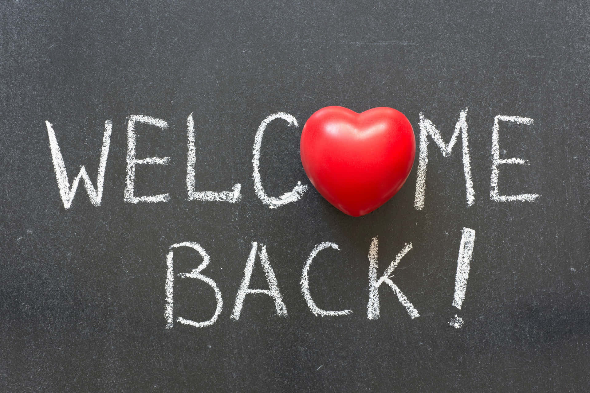  壁紙 — 一個紅色心形取代了「WELCOME BACK!」中的字母O，該訊息用白色粉筆寫在深灰色黑板上。