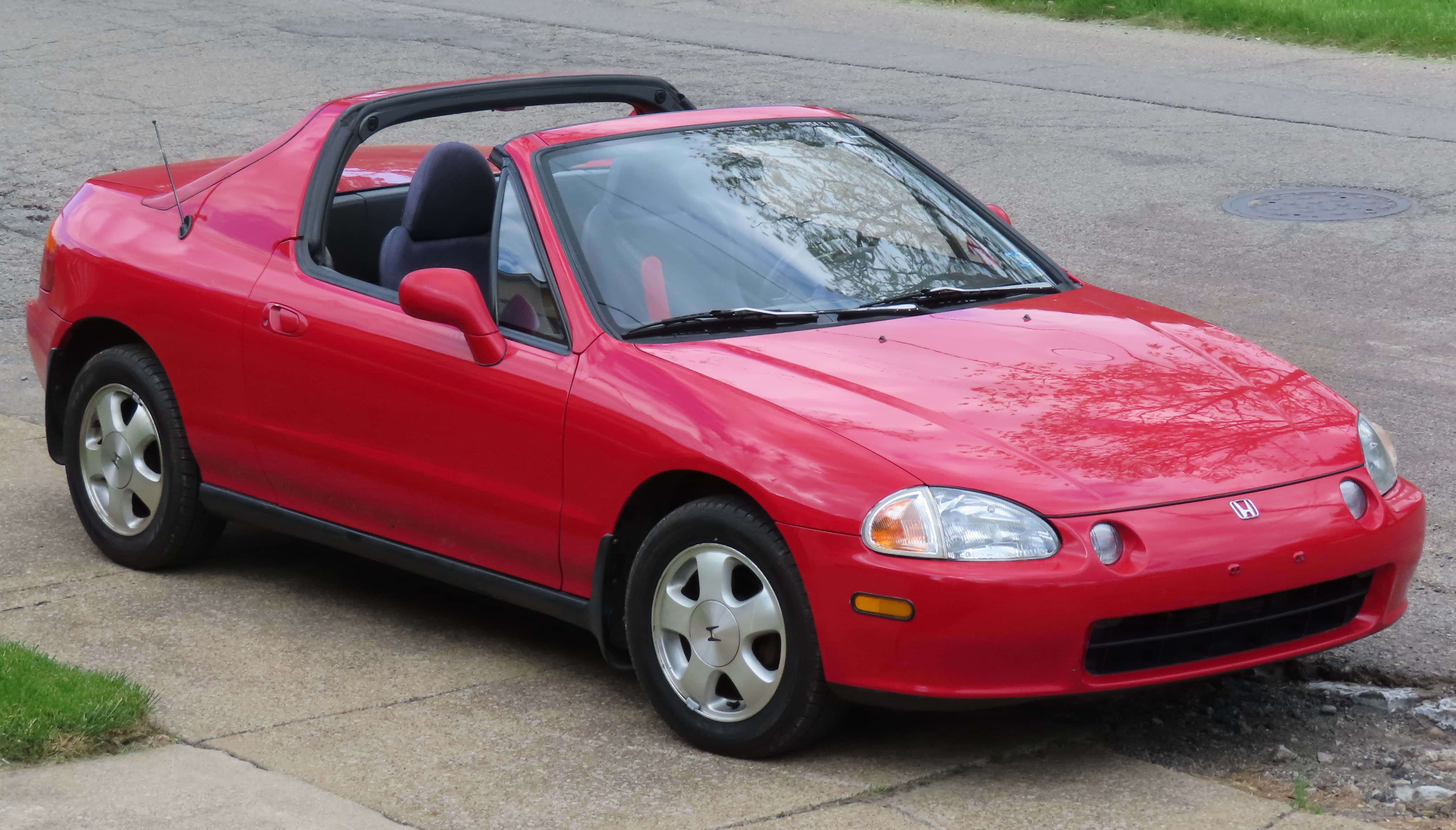 Honda Civic Del Sol 桌布 壁紙 — 一輛鮮紅色的本田 Del Sol 開篷車停泊在附近有草地和路面的行人路上。