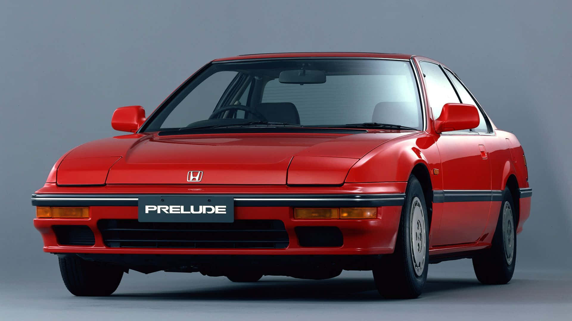 Honda Prelude 桌布 壁紙 — 一輛鮮紅色的本田Prelude運動型轎跑車在工作室燈光下，在灰色中性背景上閃閃發光。