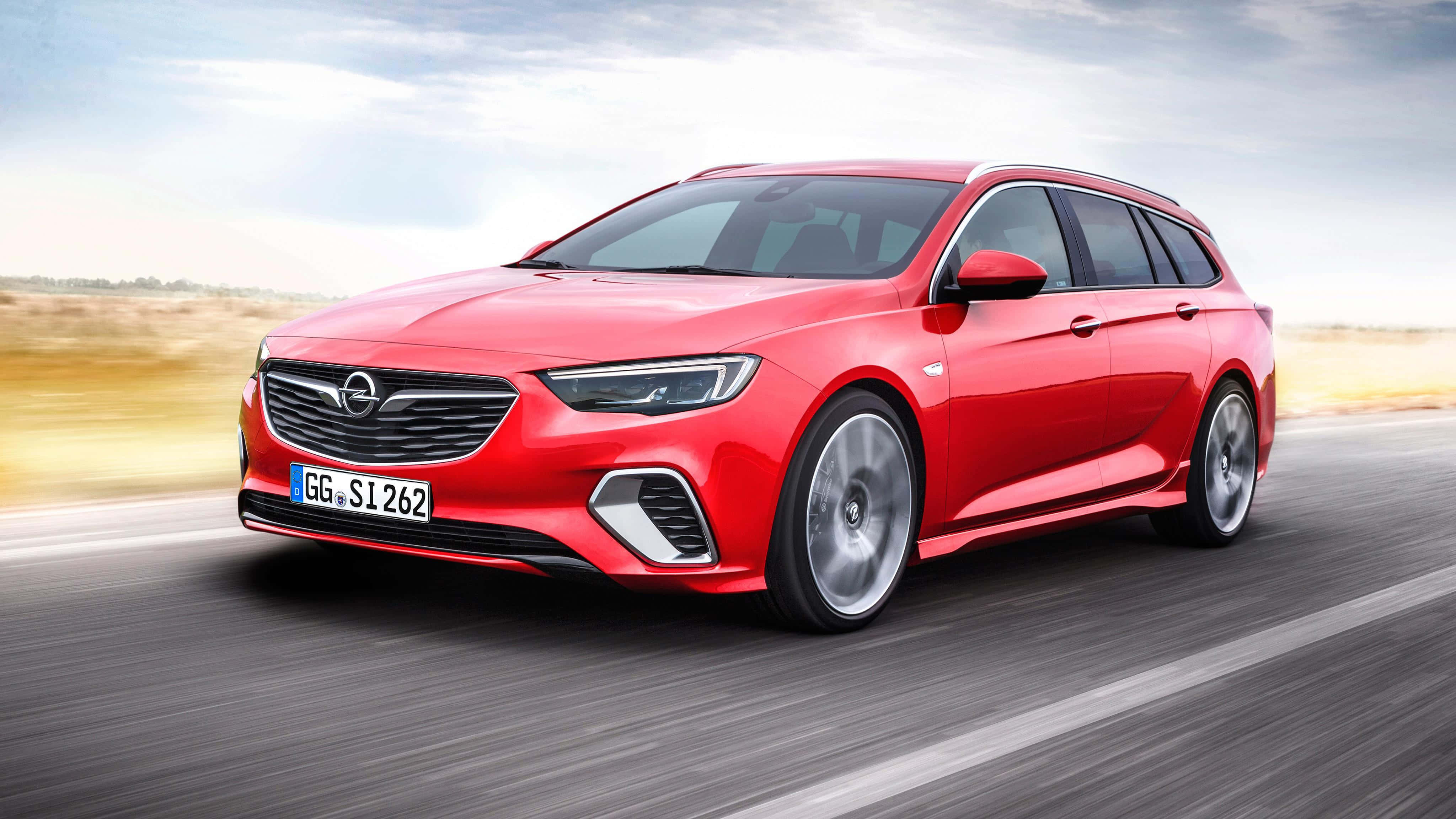 Opel Insignia 桌布 壁紙 — 一輛鮮紅色的歐寶旅行車在明亮的白天天空下，在模糊的高速公路上疾馳。