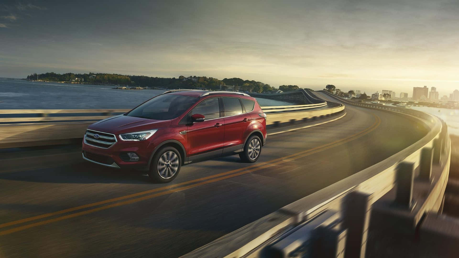 Ford Escape 桌布 壁紙 — 一輛紅色SUV在日落時分沿著蜿蜒的海岸公路行駛，遠處是城市天際線。