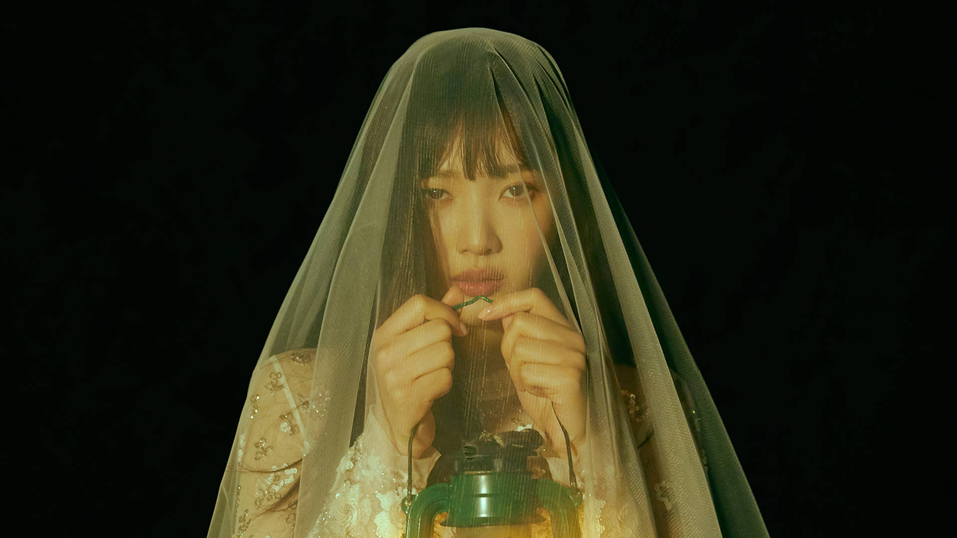一位戴著面紗的女子在黑暗環境中手持發光的燈籠。