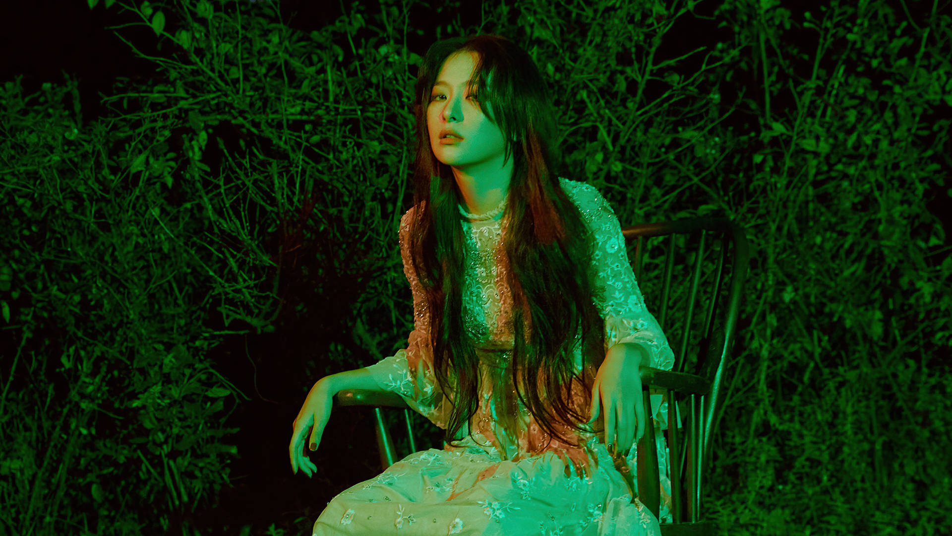 夜晚在綠色燈光森林中坐在椅子上的花卉連衣裙女性