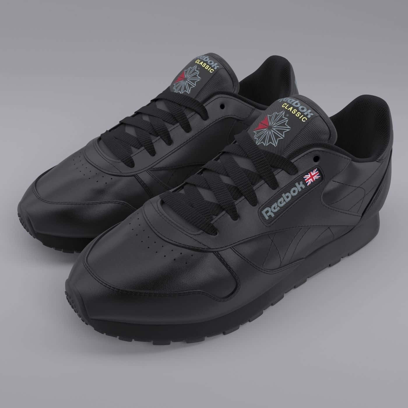 用Reebok提升你的表現 壁紙 — 一對黑色Reebok Classic運動鞋，帶有微妙的紅色和灰色點綴，在灰色中性背景上展示。