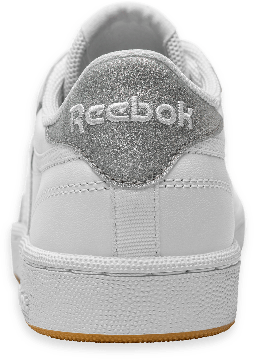 Reebok Classic 鞋款後跟視圖 壁紙 — 白色Reebok運動鞋特寫，帶閃亮銀色後跟標籤和橡膠鞋底，背景為綠色。