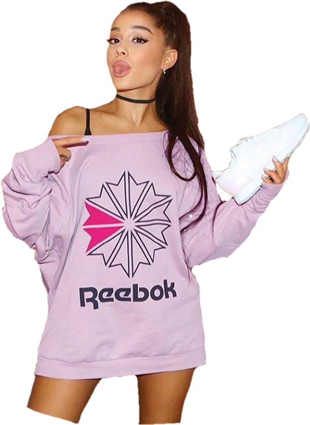 Reebok明星宣傳圖 壁紙 — Ariana Grande 身穿淡紫色 Reebok 衛衣，在黑色背景前俏皮地拿著白色運動鞋擺姿勢。