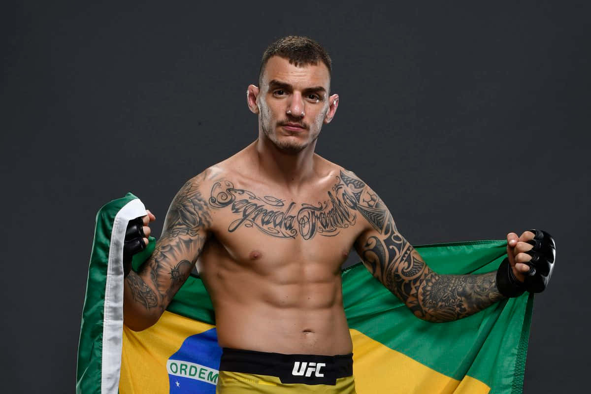 「Renato Moicano，巴西MMA的驕傲」 壁紙 — 一位肌肉發達、有紋身的戰士在黑暗的攝影棚背景下將巴西國旗披在肩上。