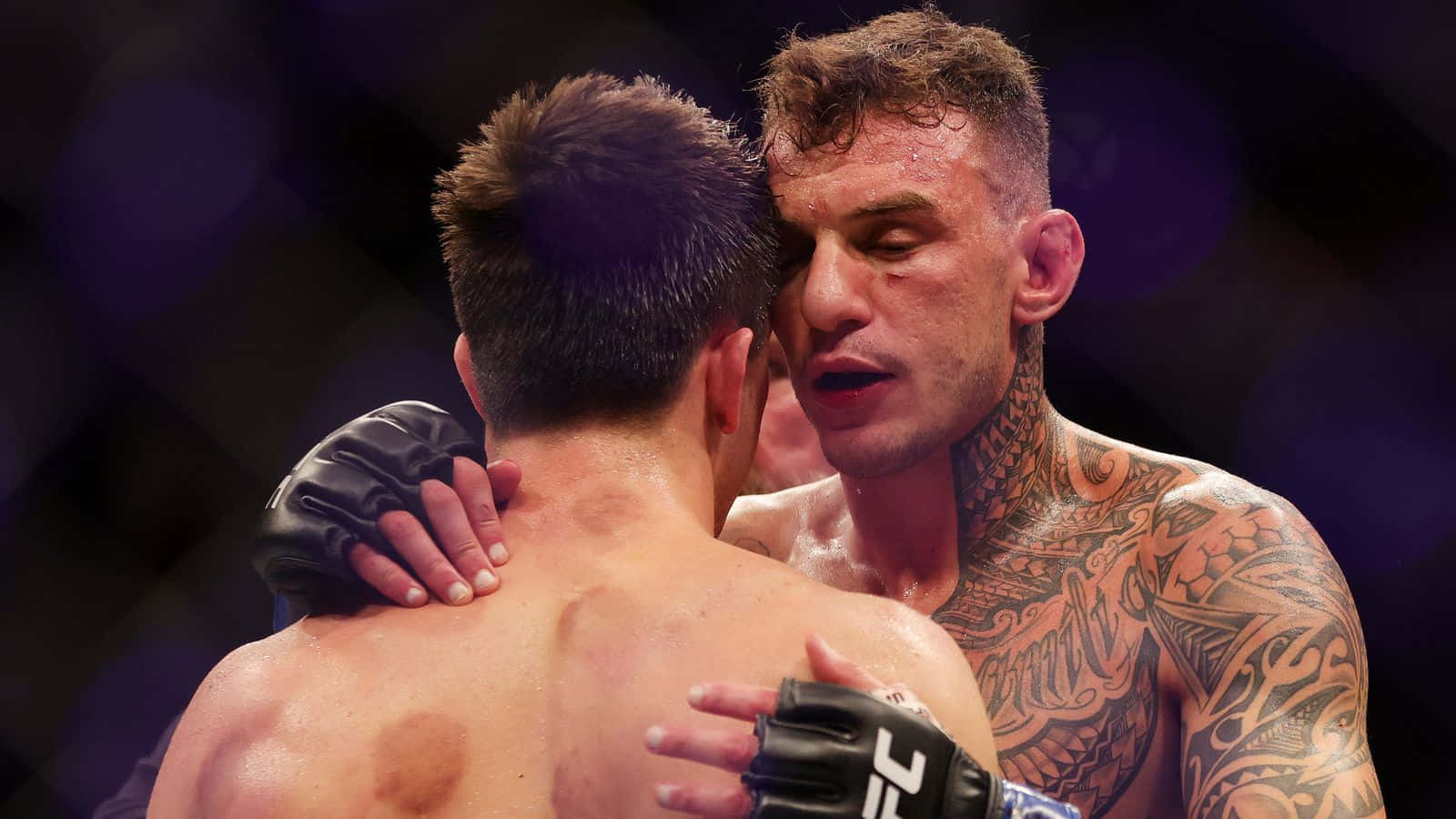 兩名筋疲力竭的MMA拳手在八角籠中賽後擁抱。