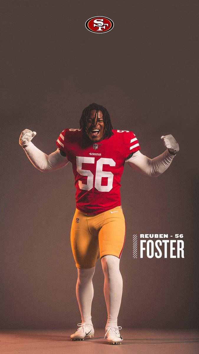 Reuben Foster 聖地牙哥49人隊 壁紙 — 一名身穿紅金色球衣的三藩市四九人美式足球員在黑色攝影棚背景下高舉拳頭慶祝。