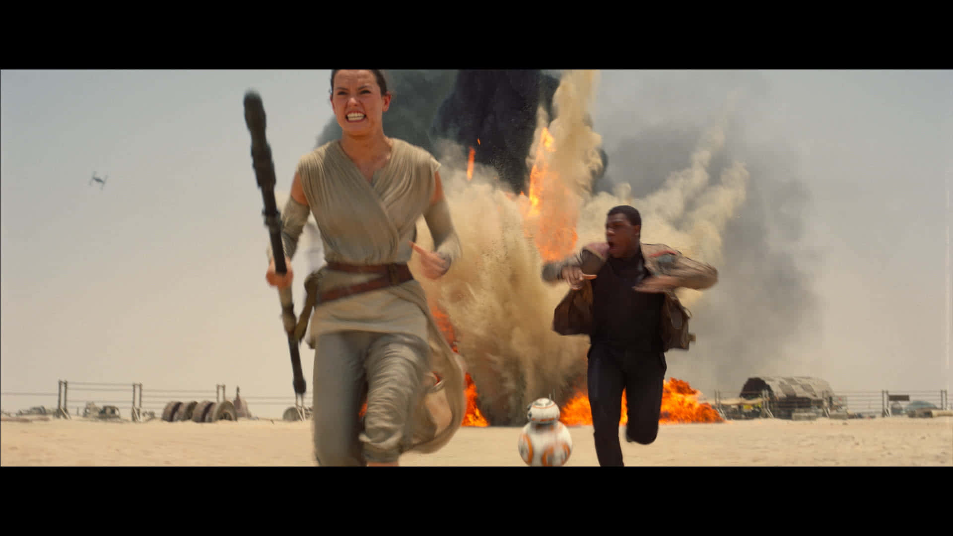 Jakku 桌布 壁紙 — Rey和Finn在沙漠戰場上奔跑，身後爆炸四起，BB-8在附近滾動。