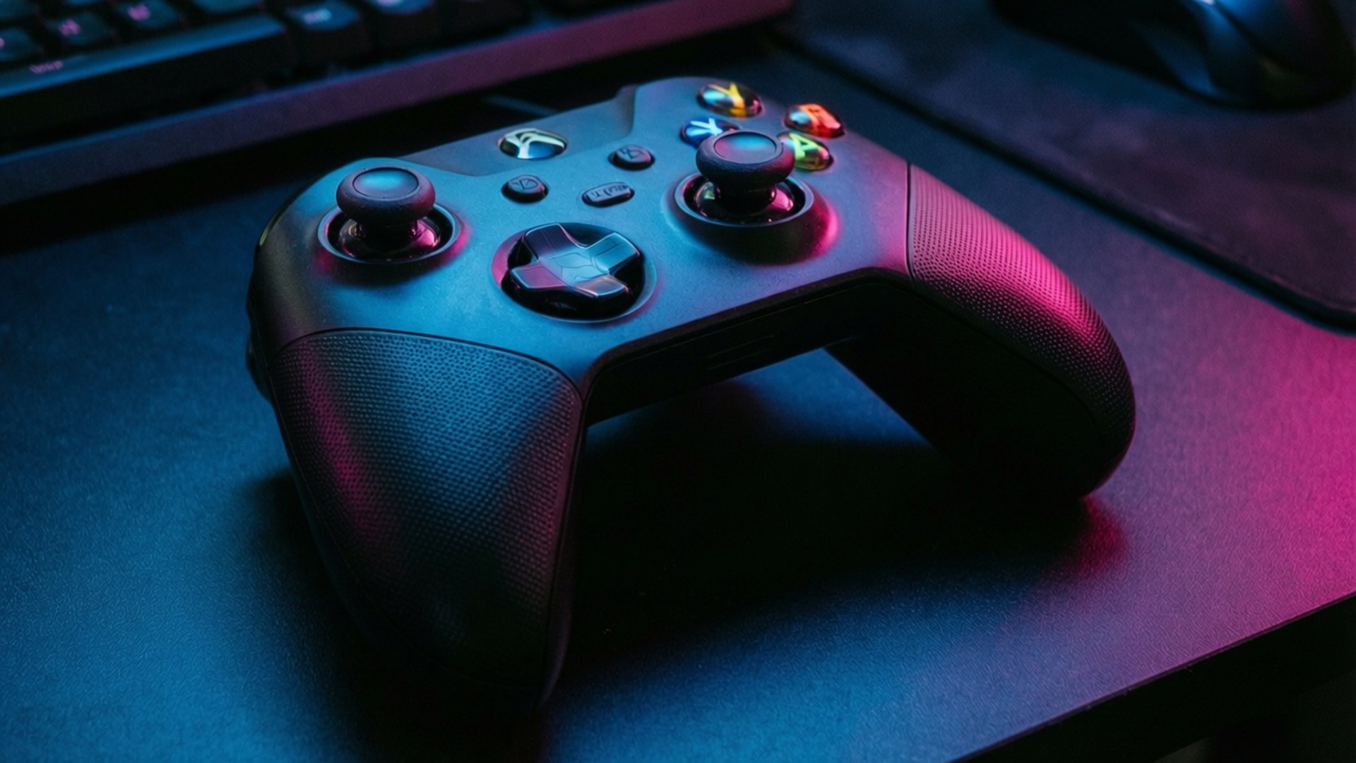 黑色Xbox手掣在遊戲桌上的藍色和粉紅色霓虹燈下發光。