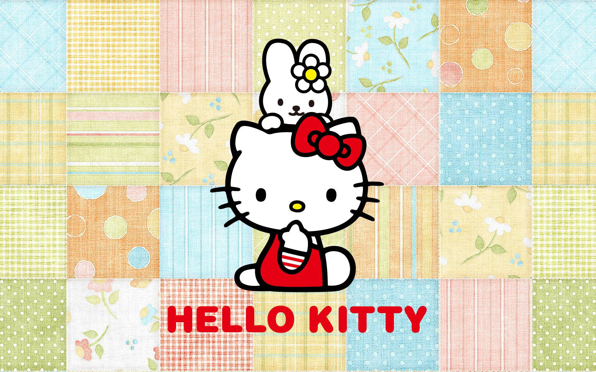 Rhythm與Hello Kitty桌面 壁紙 — Hello Kitty 和她的朋友坐在色彩繽紛的拼布被子背景上，帶有花卉和幾何圖案。